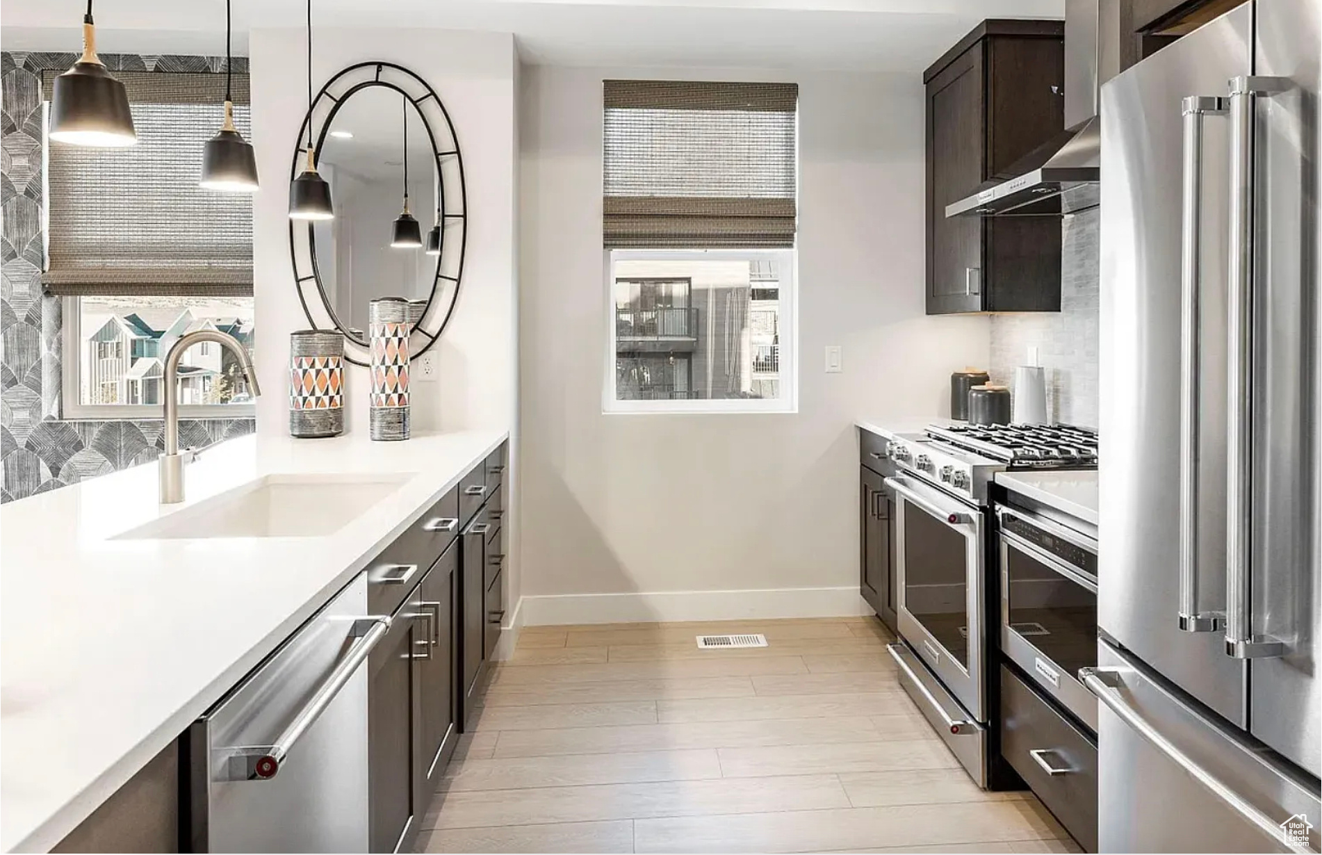 Kitchen featuring light countertops, premium appliances, backsplash, and a sink