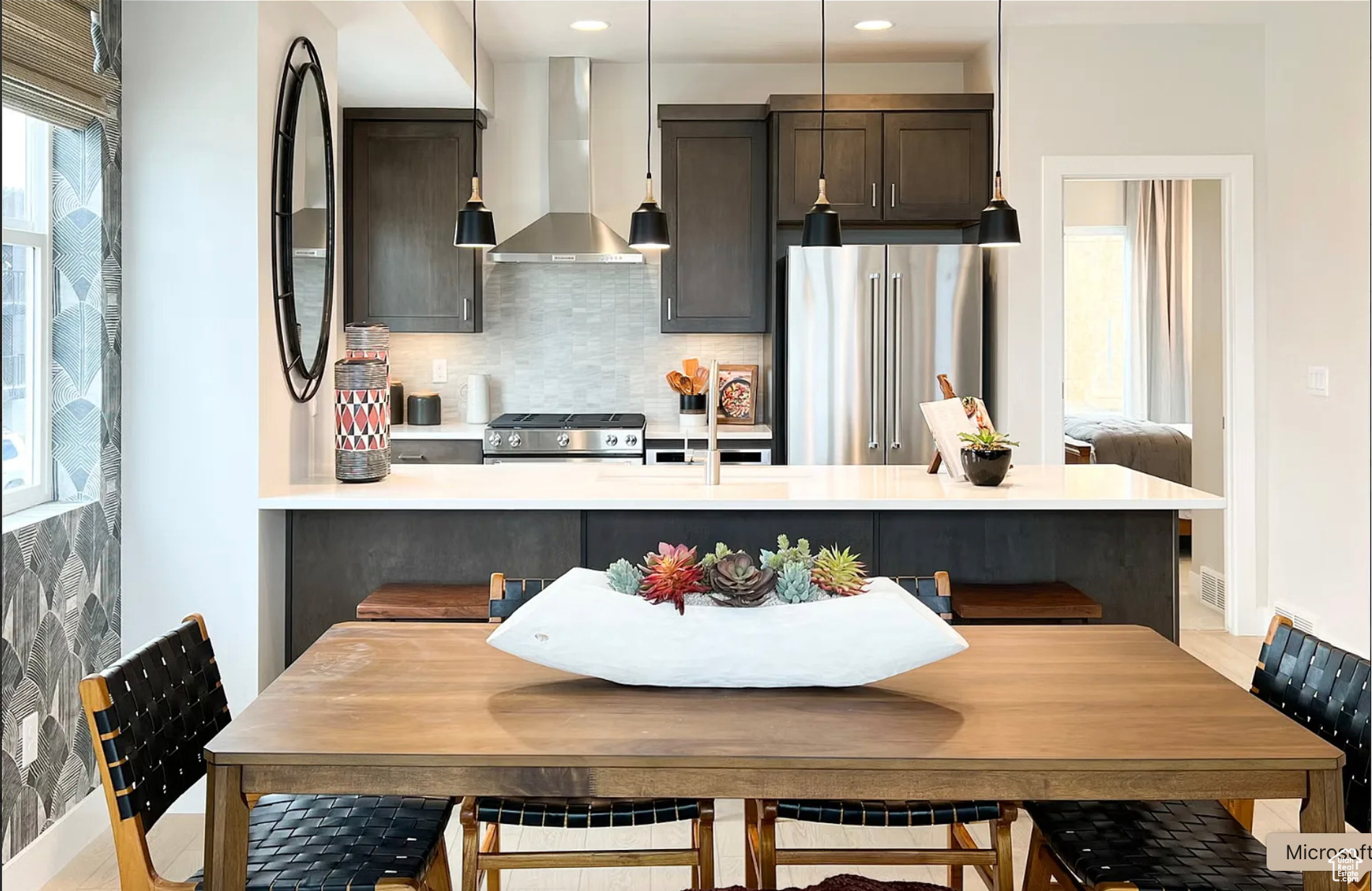 Kitchen with range, decorative light fixtures, light countertops, wall chimney range hood, and high end fridge