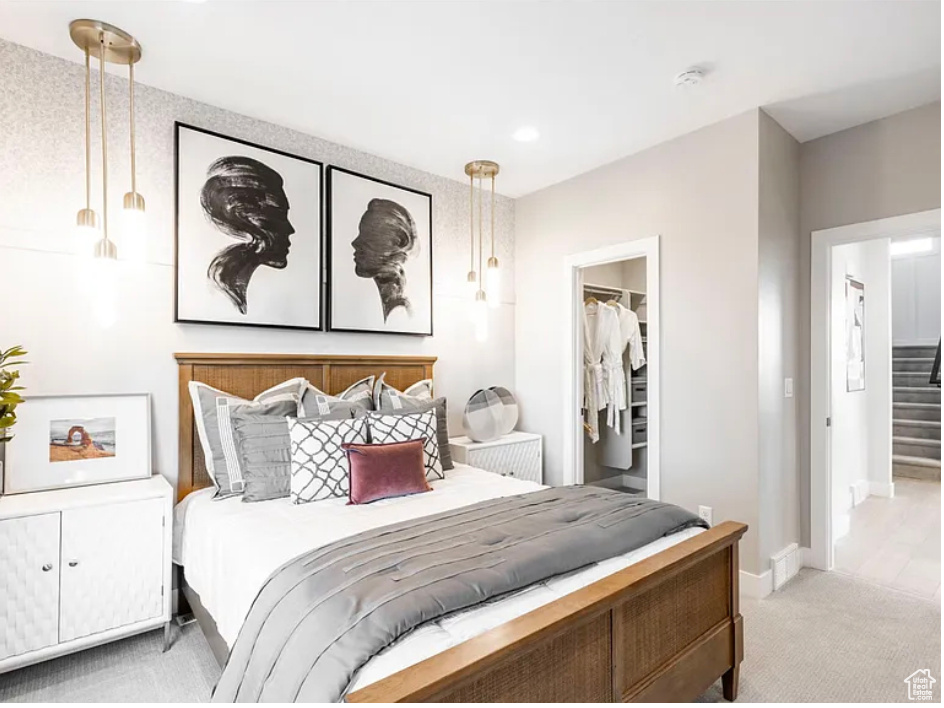 Bedroom featuring a closet, light carpet, a spacious closet, and baseboards