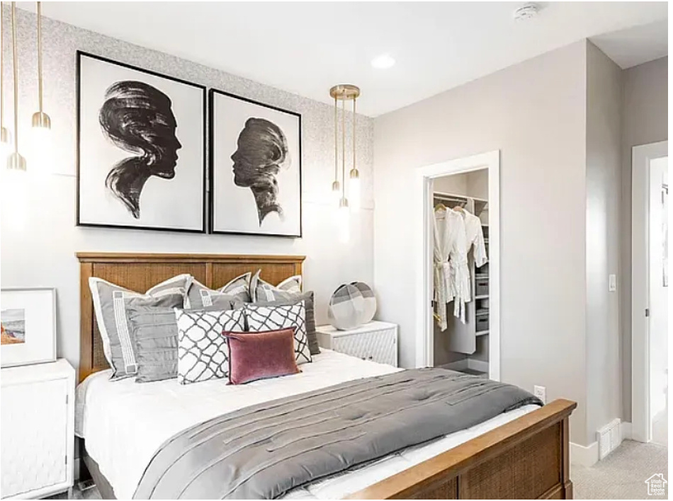 Bedroom with light carpet, a closet, a walk in closet, and baseboards