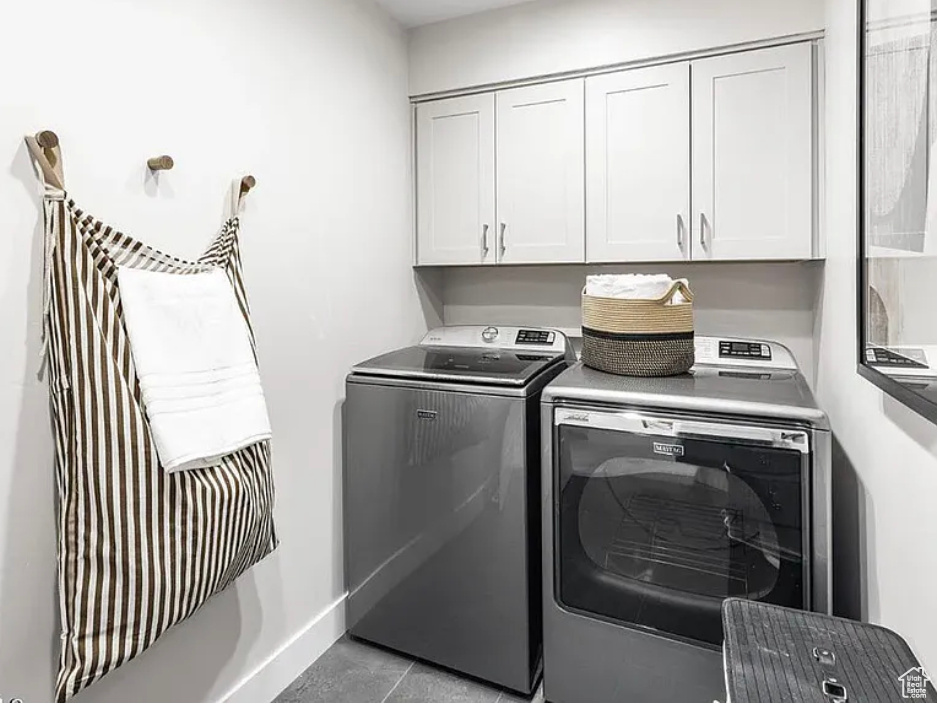 Laundry room featuring cabinet space, washing machine and dryer, and light tile patterned floors