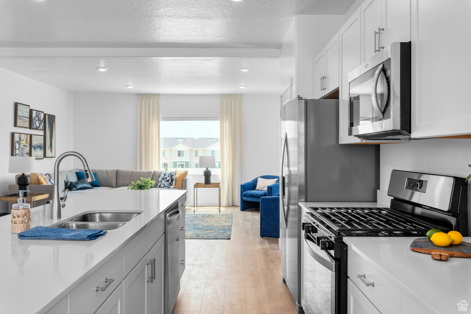 Kitchen with a sink, stainless steel appliances, open floor plan, and light countertops