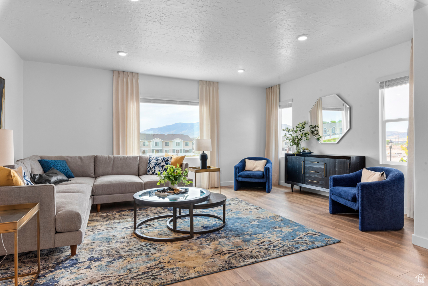 Living room with light wood-style flooring, a textured ceiling, and recessed lighting