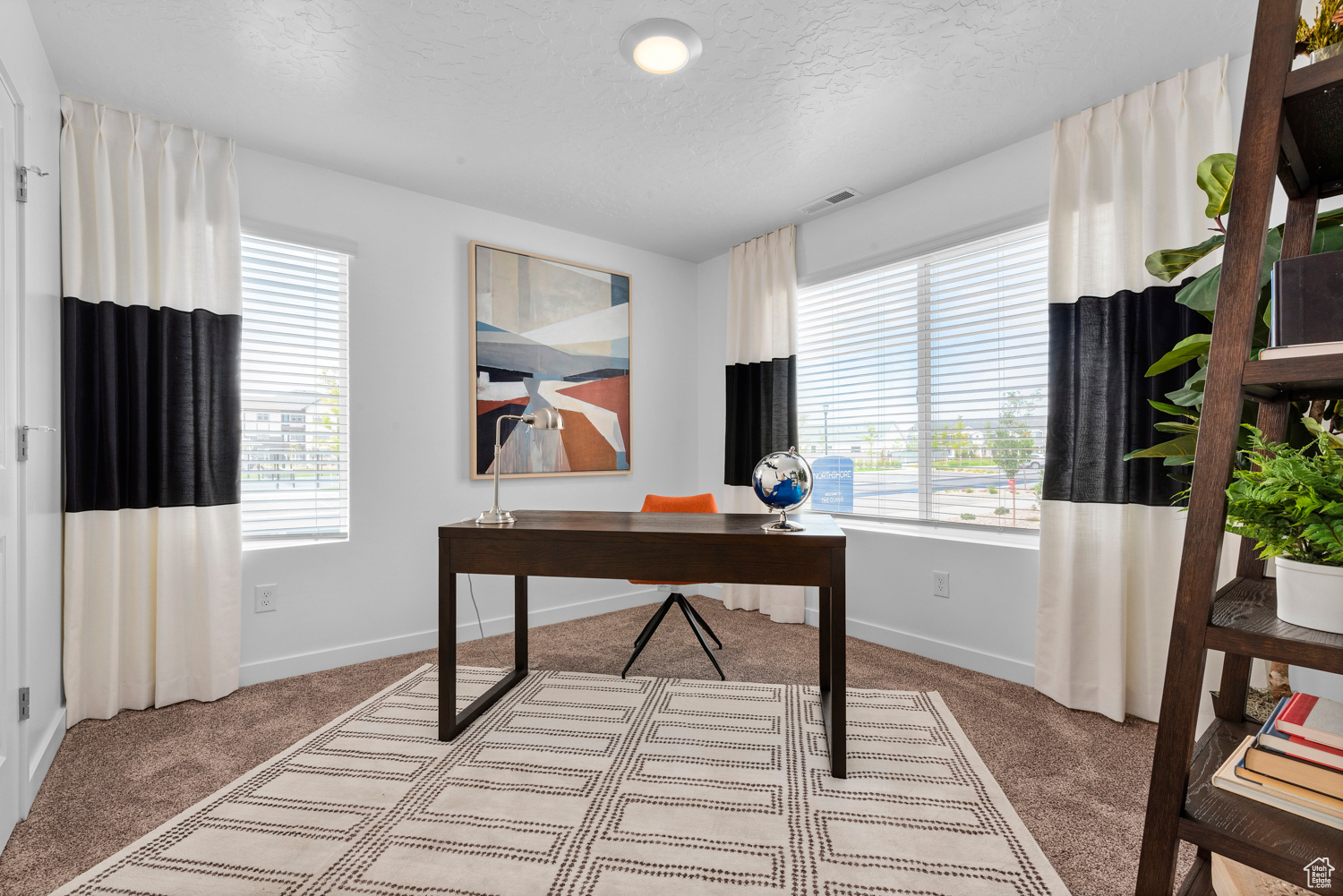 Office with carpet floors, a textured ceiling, visible vents, and a wealth of natural light