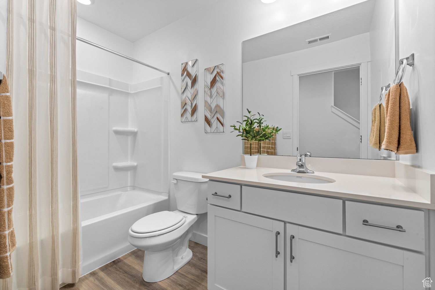Bathroom with shower / bath combination, visible vents, toilet, wood finished floors, and vanity
