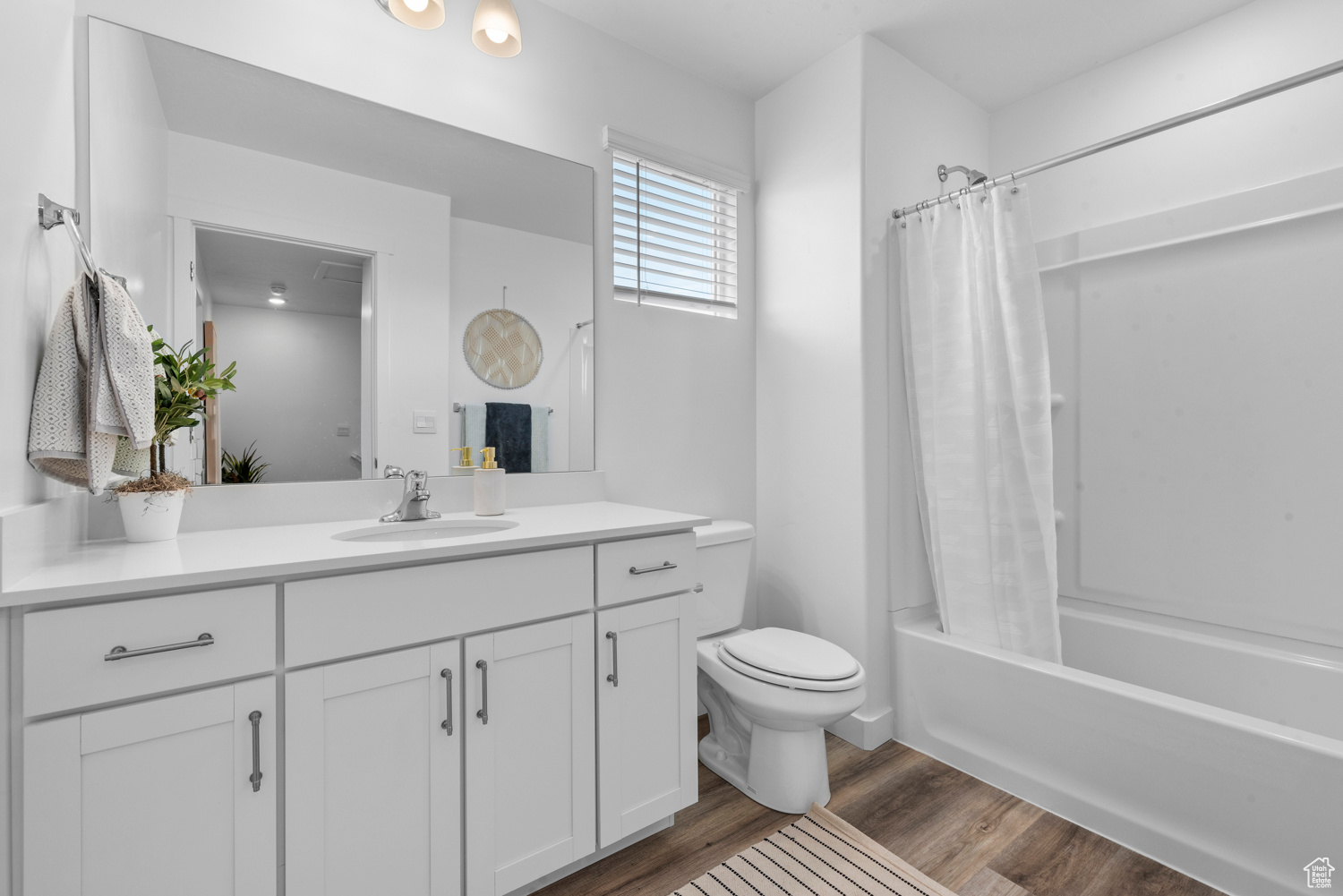 Full bath with toilet, shower / bath combo with shower curtain, wood finished floors, and vanity