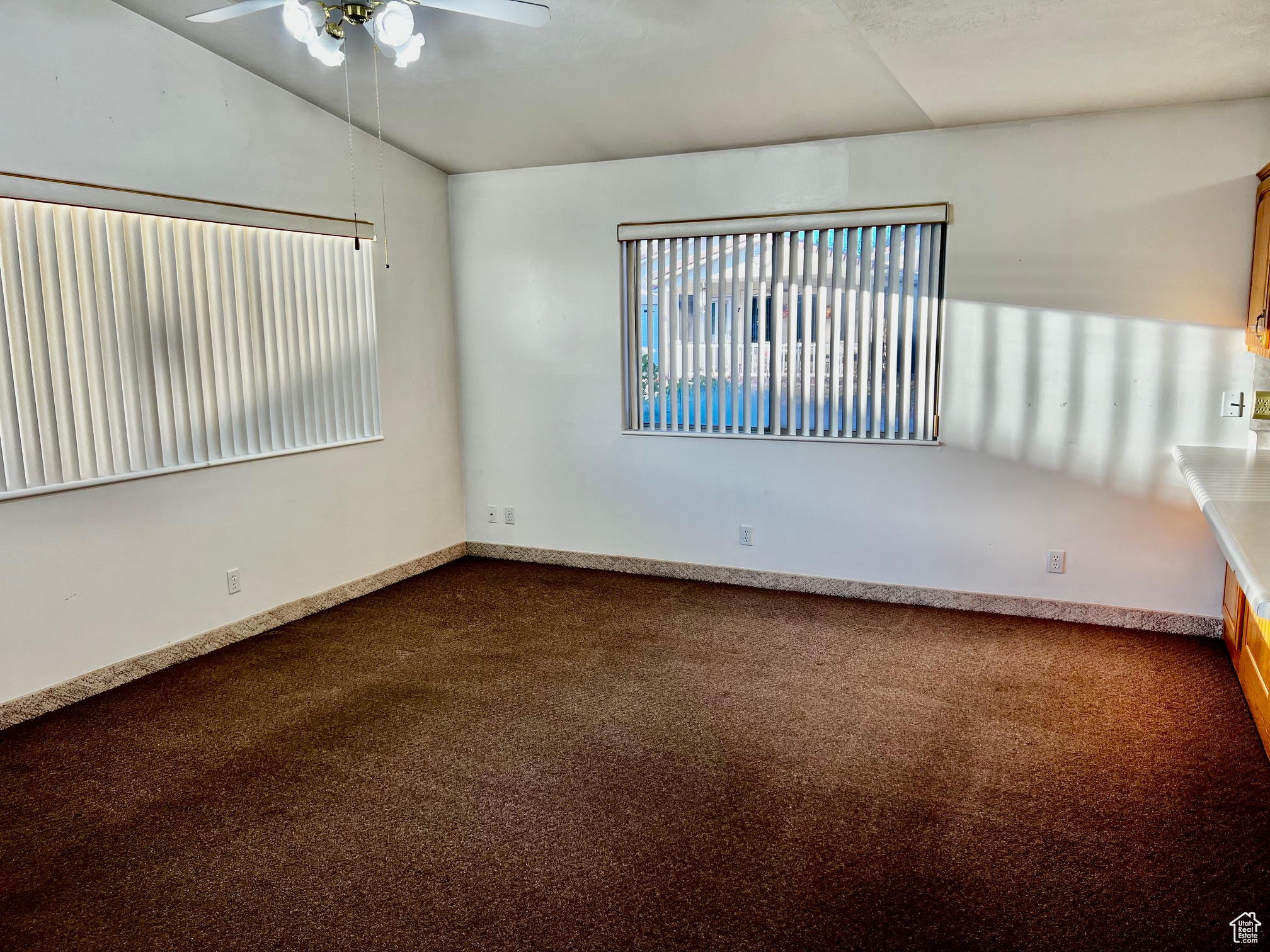 Empty room featuring a ceiling fan, baseboards, and carpet flooring