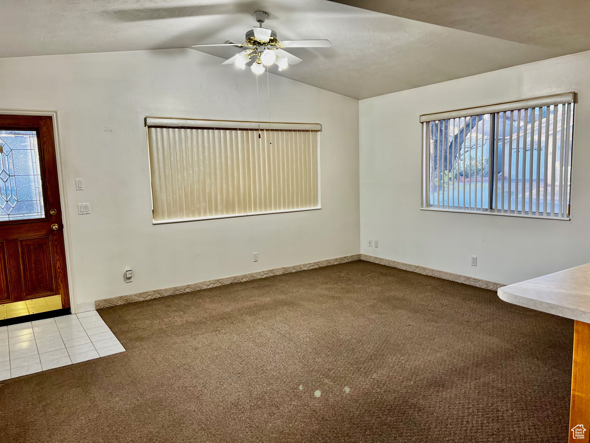 Interior space with carpet floors, a ceiling fan, a wealth of natural light, and lofted ceiling