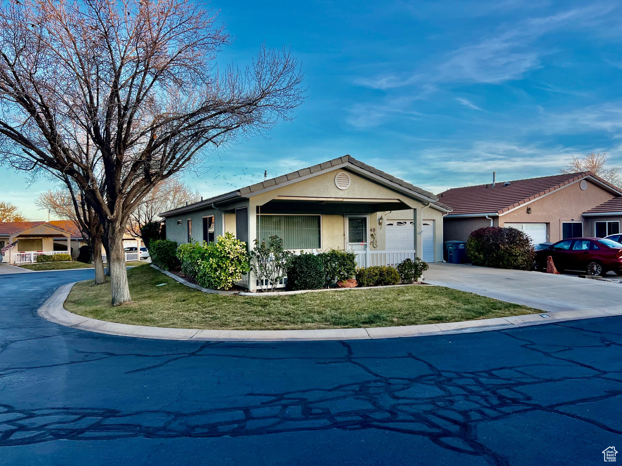 Ranch-style house featuring stucco siding, a porch, concrete driveway, a garage, and a front lawn