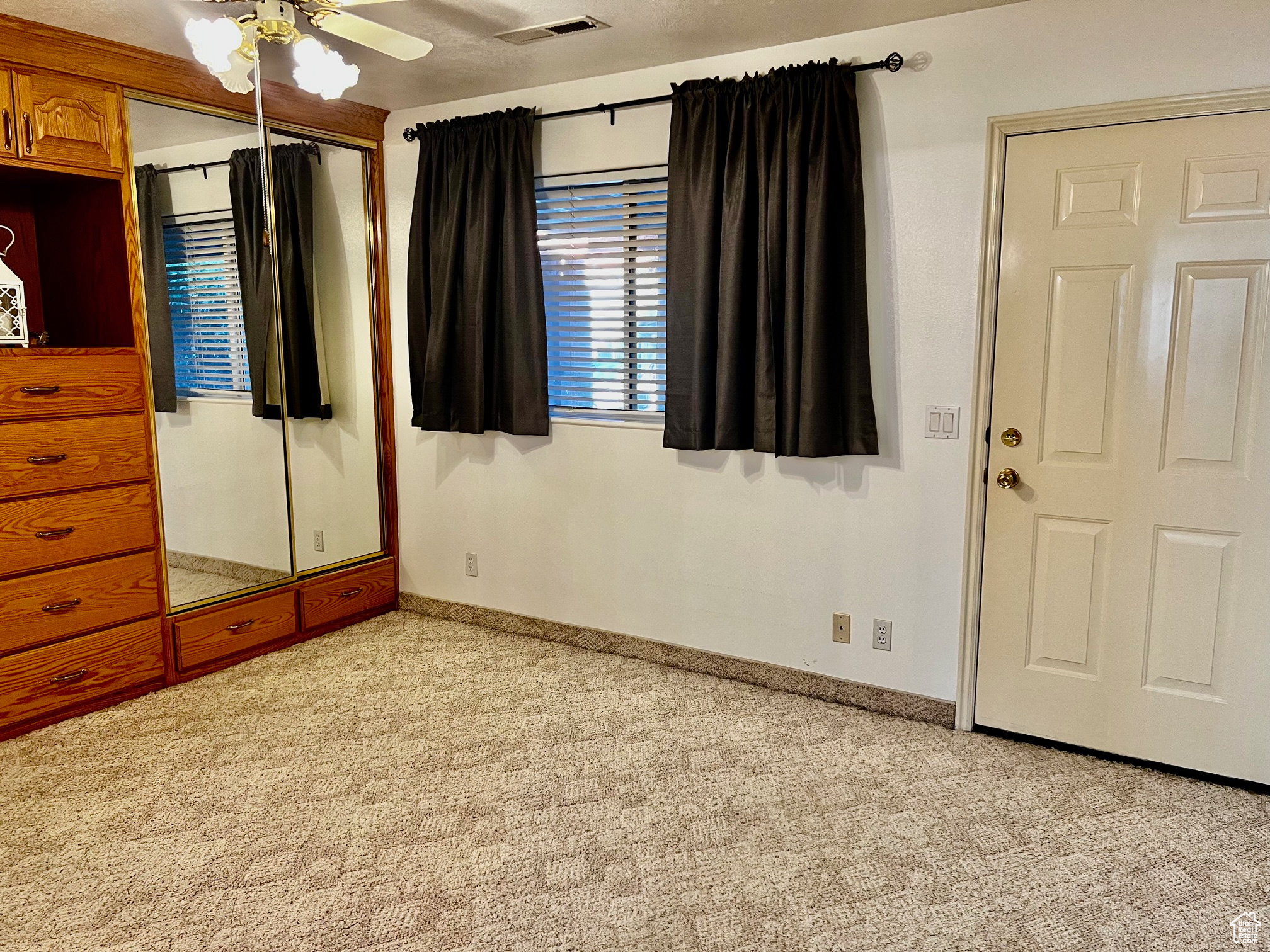 Unfurnished bedroom featuring ceiling fan, light carpet, visible vents, baseboards, and a closet