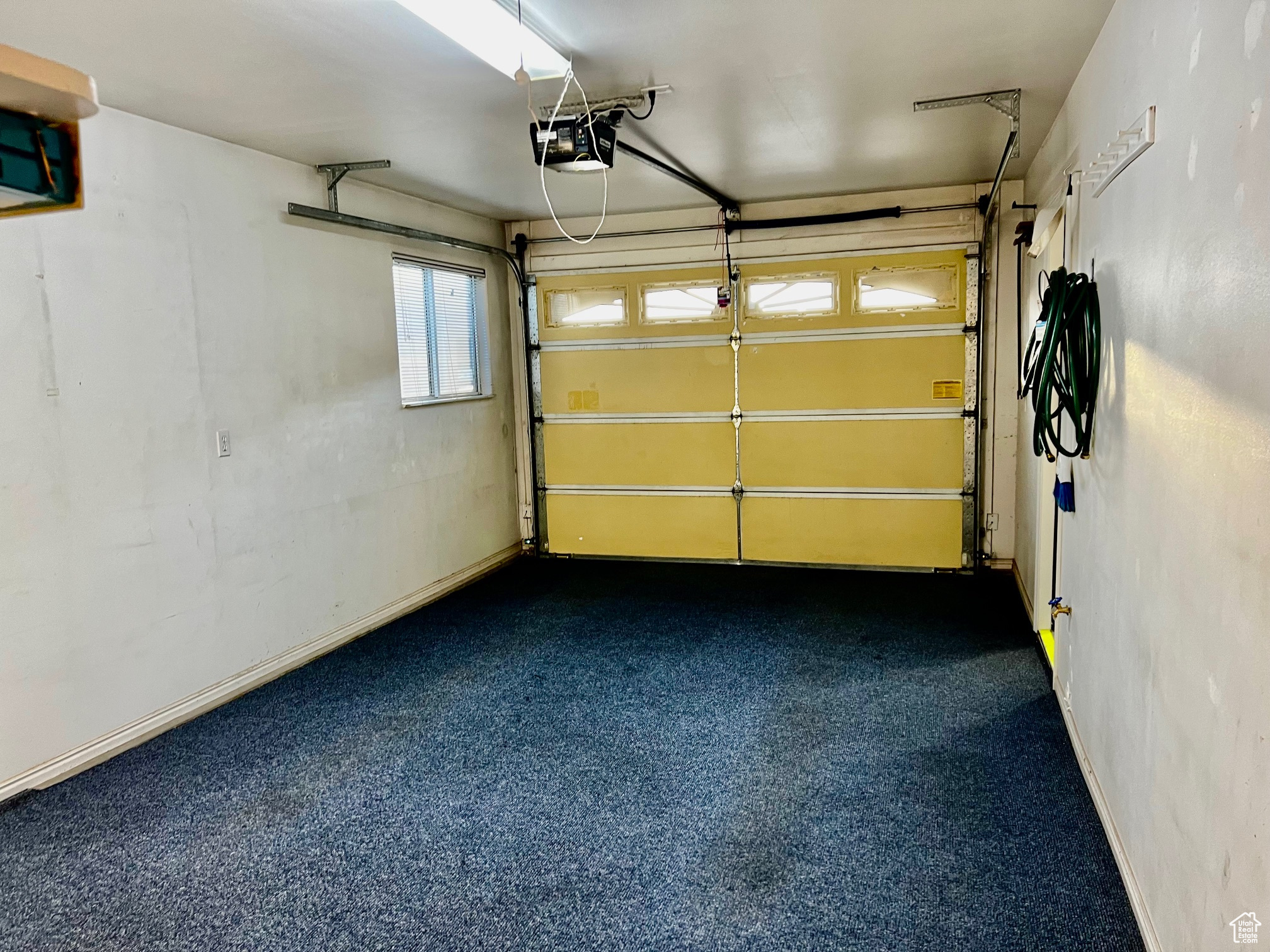 Garage featuring baseboards and a garage door opener