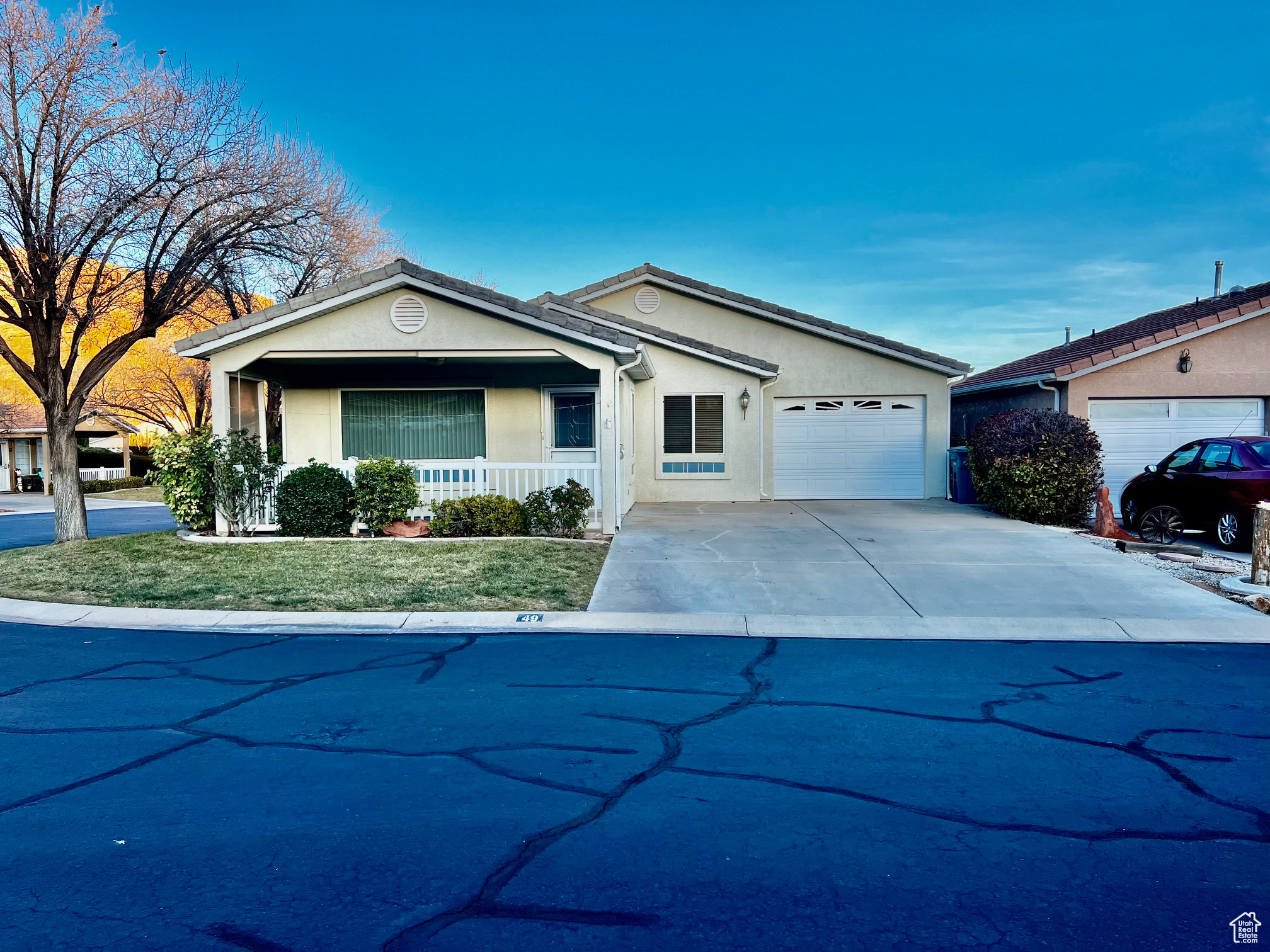 Ranch-style house featuring covered porch, driveway, an attached garage, and stucco siding
