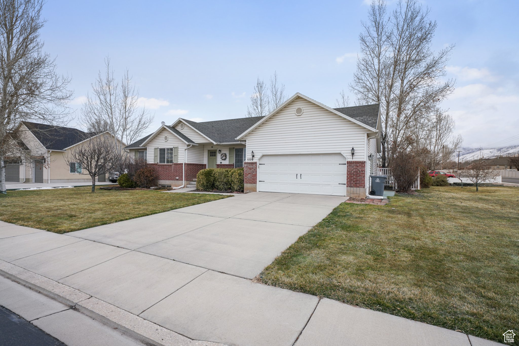 Single story home featuring a garage, a front lawn, concrete driveway, and brick siding