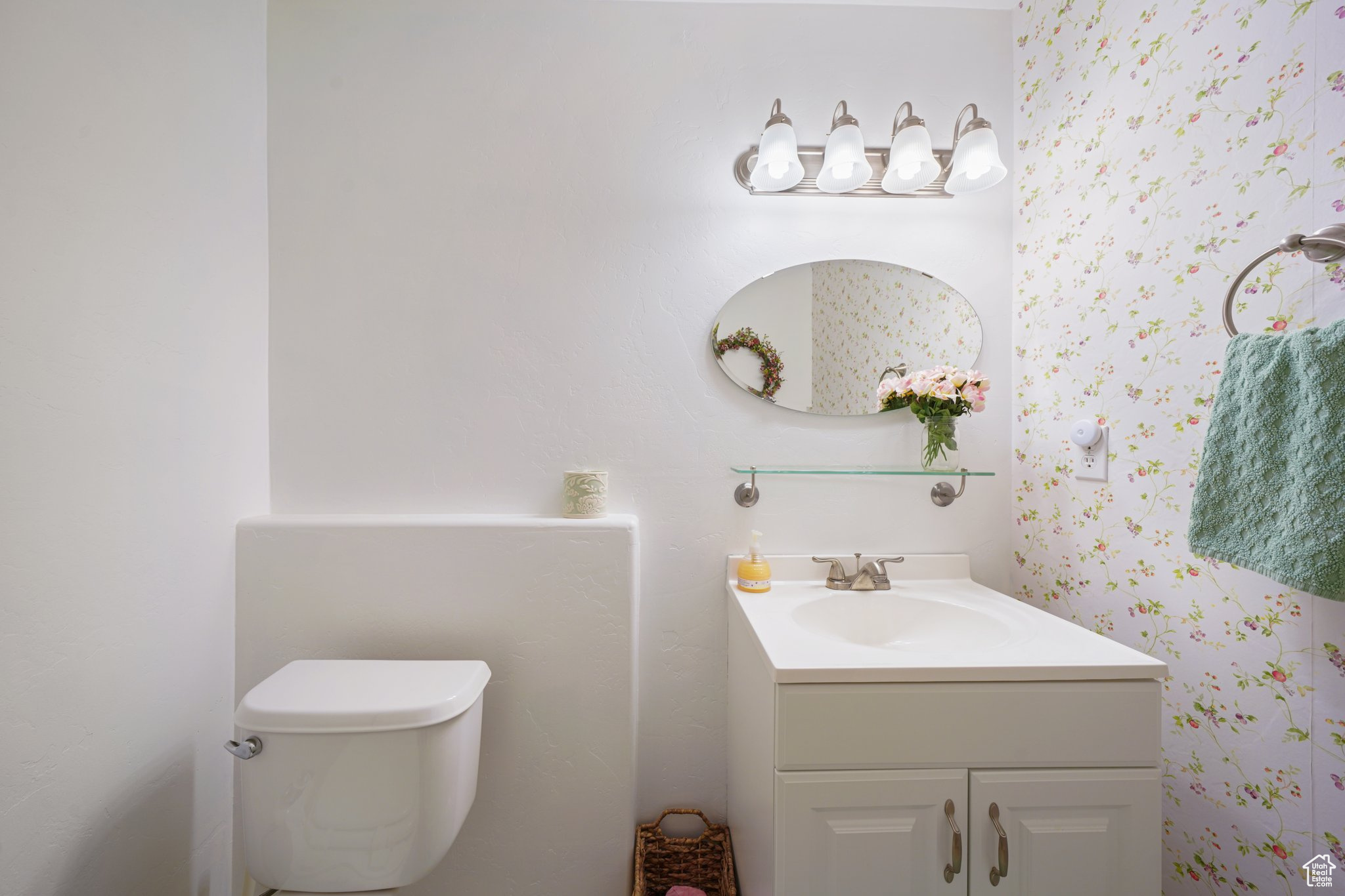 Bathroom with toilet, vanity, and wallpapered walls