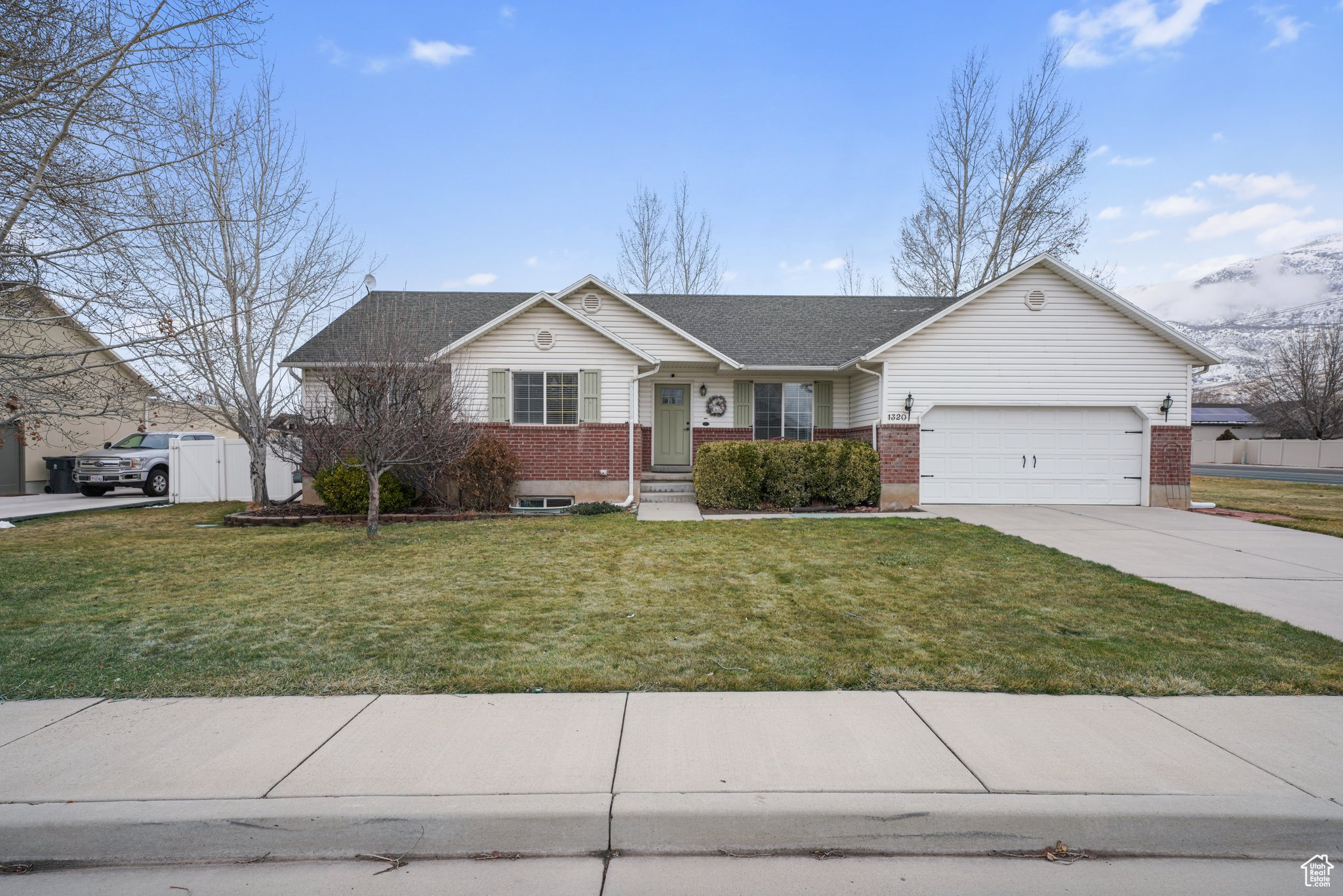 Single story home with a garage, concrete driveway, brick siding, and a front yard