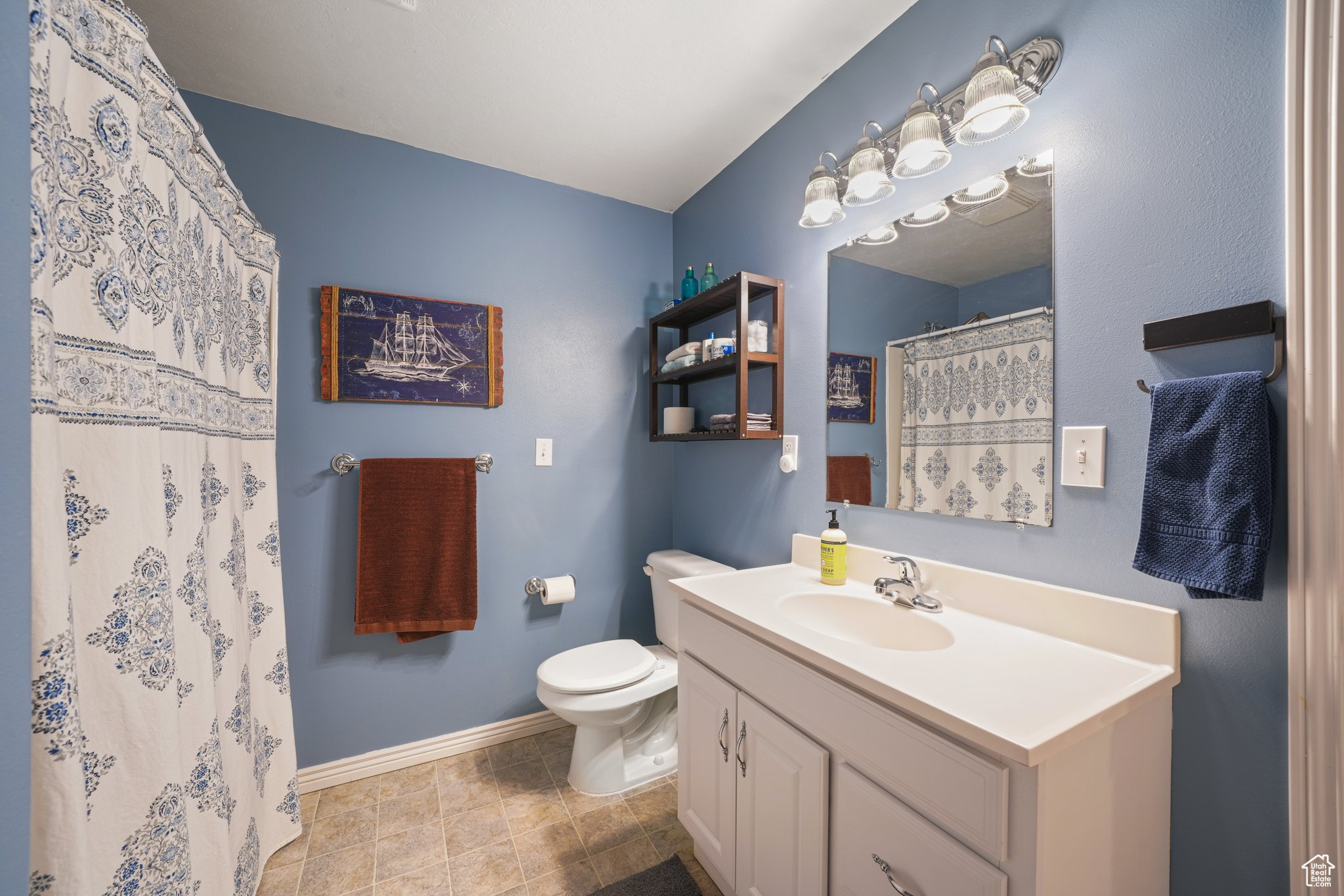 Full bath with a shower with curtain, baseboards, vanity, and toilet