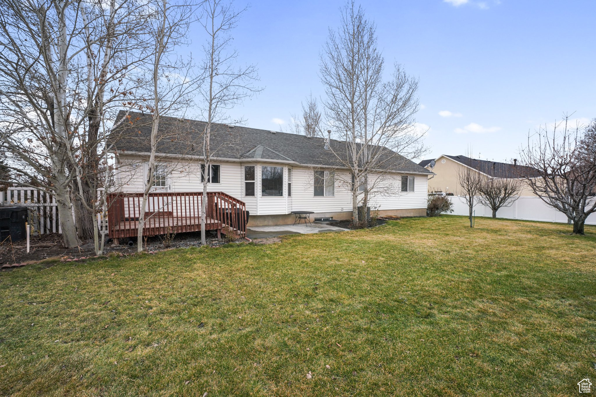 Rear view of house with a lawn, a wooden deck, and fence