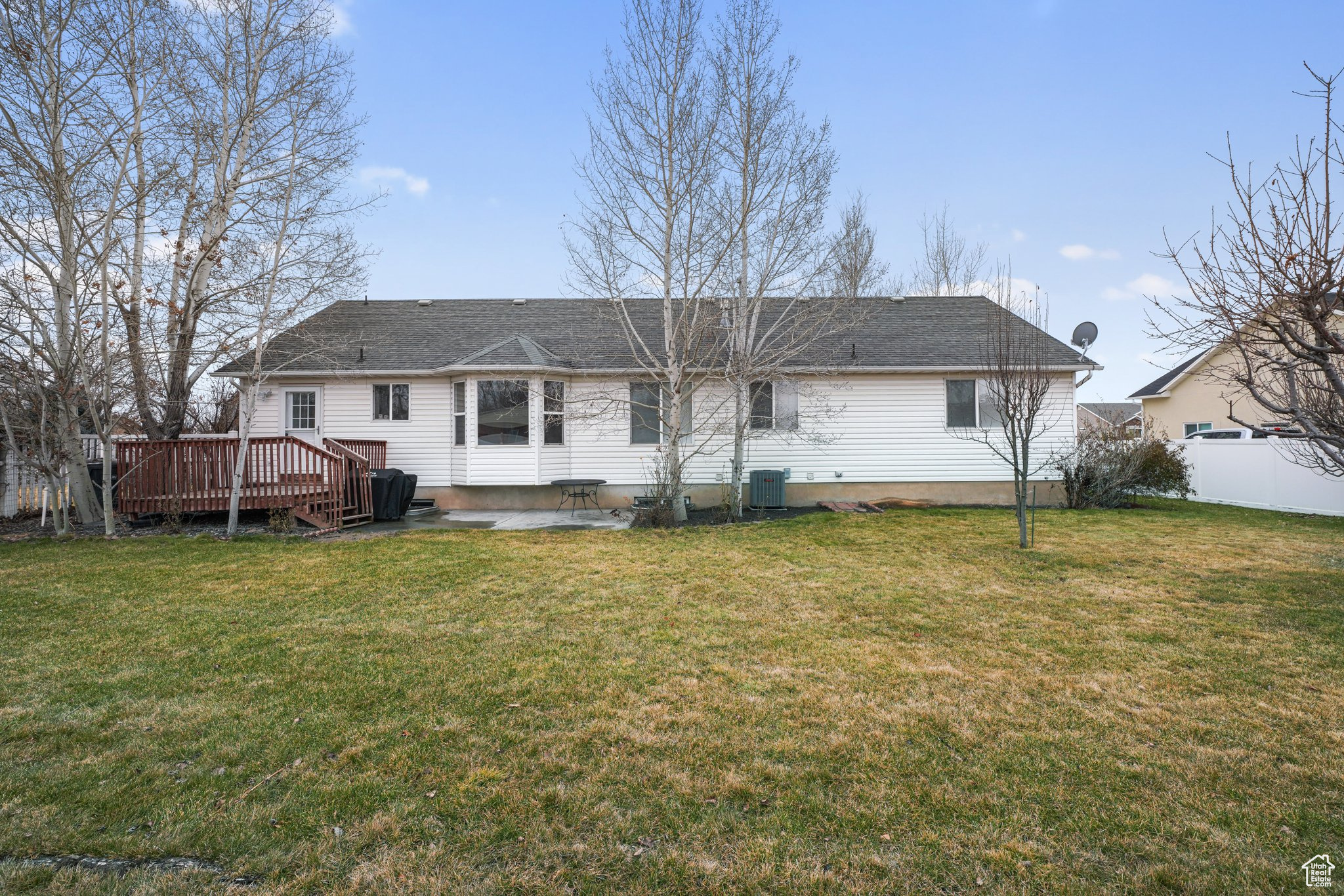 Rear view of house featuring roof with shingles, central air condition unit, a lawn, fence, and a deck