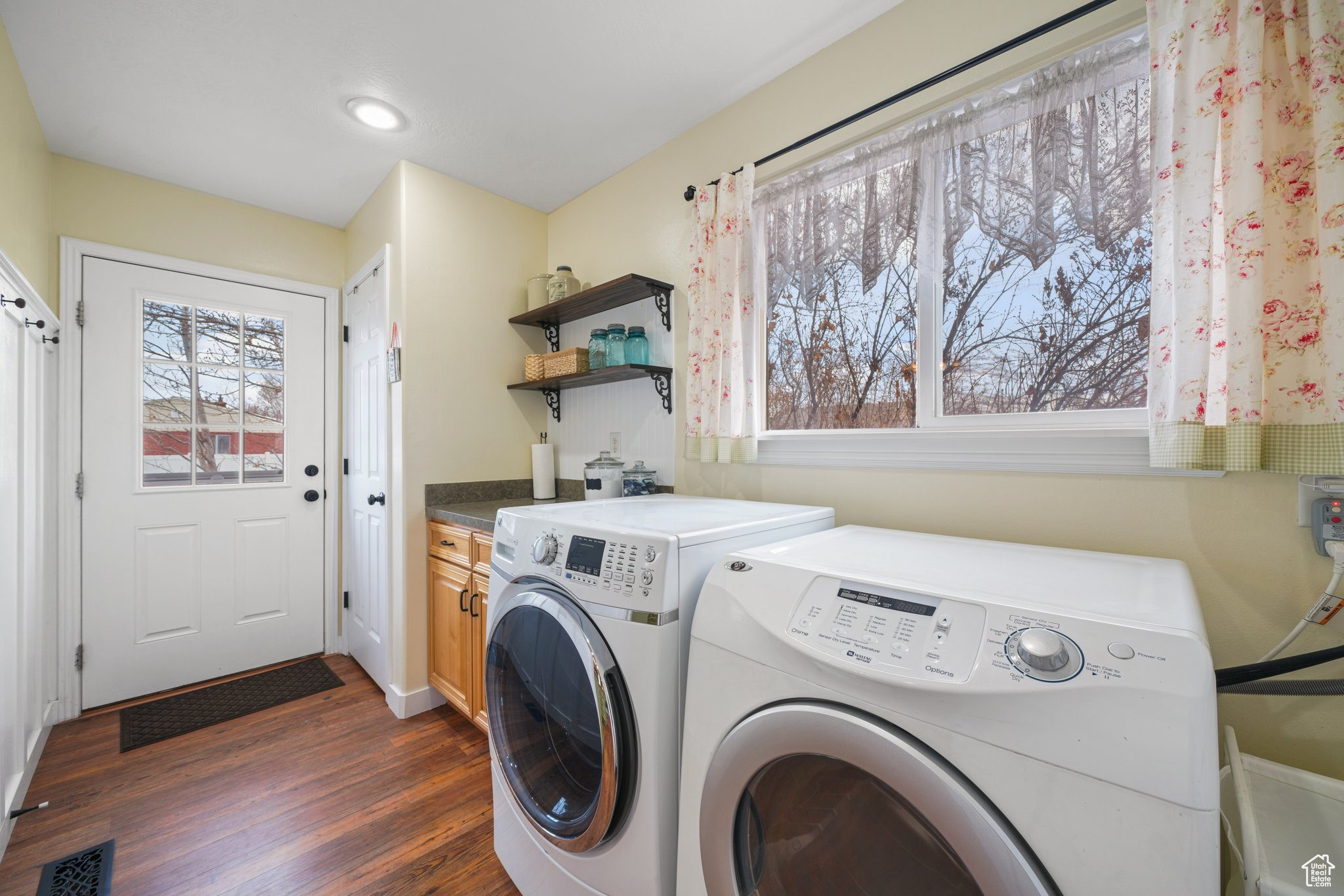 Laundry area featuring dark wood-style floors, visible vents, independent washer and dryer, and cabinet space