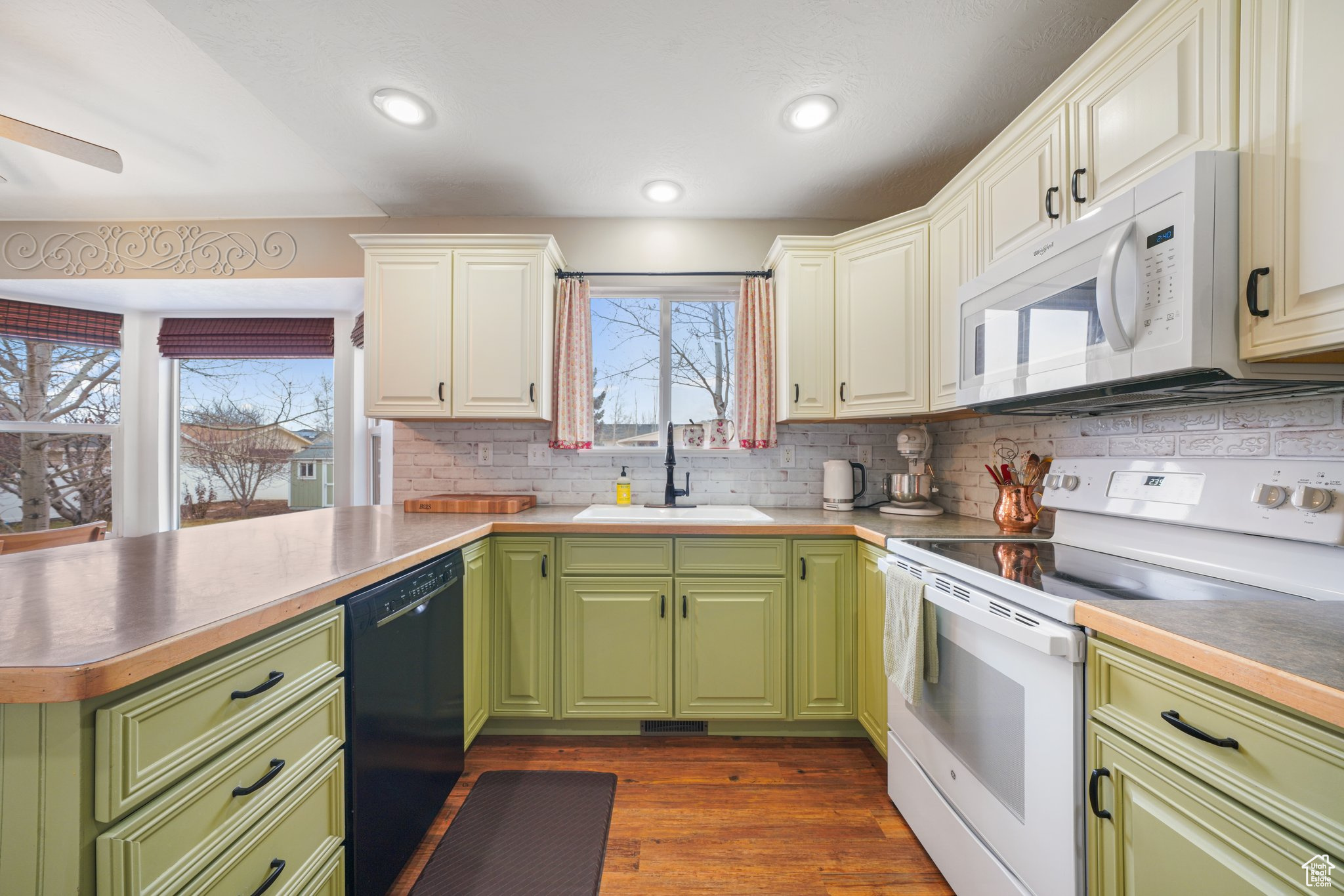 Kitchen with white appliances, a sink, white cabinetry, backsplash, and dark wood finished floors