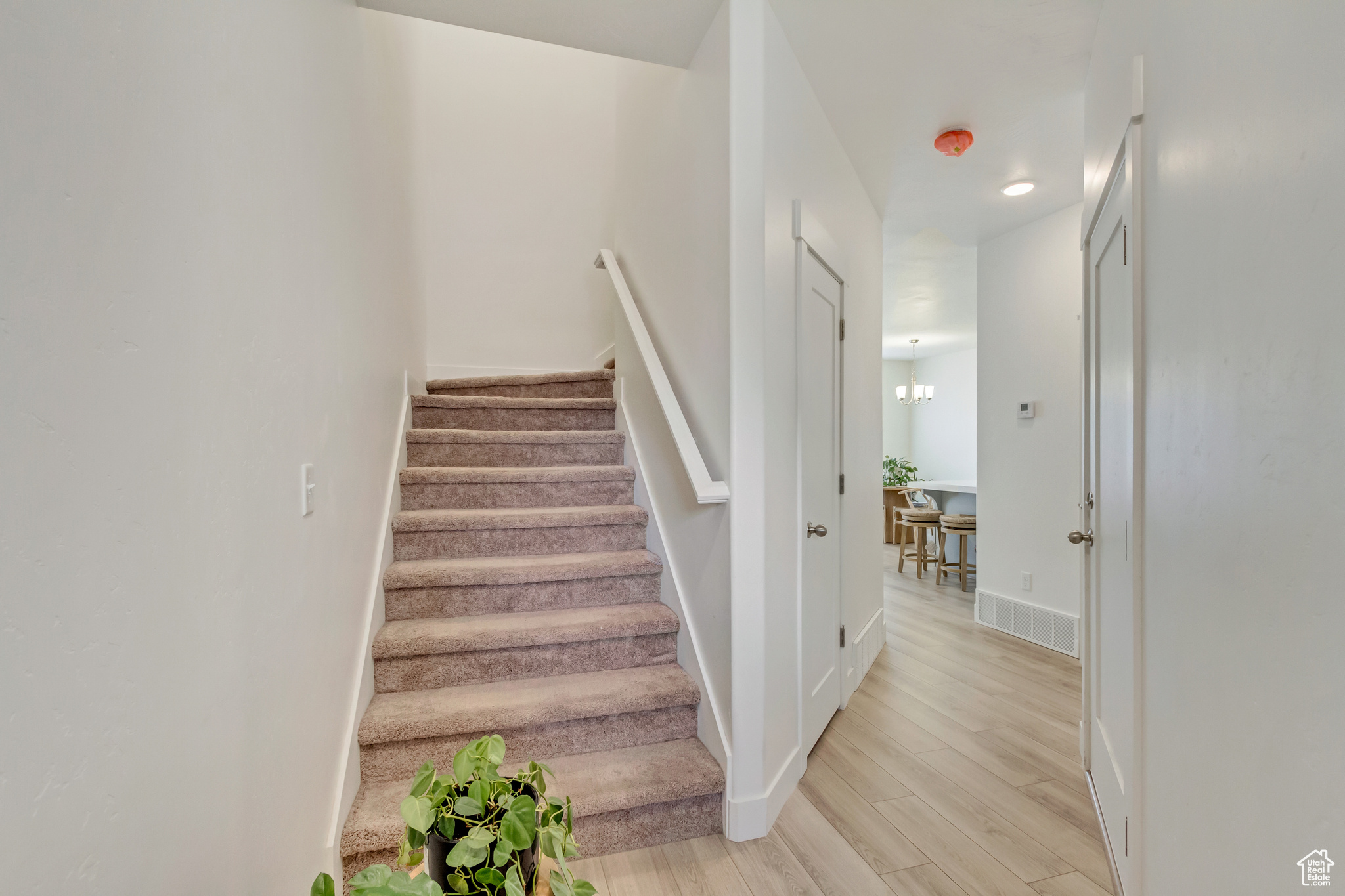 Staircase featuring visible vents, a notable chandelier, baseboards, and wood finished floors