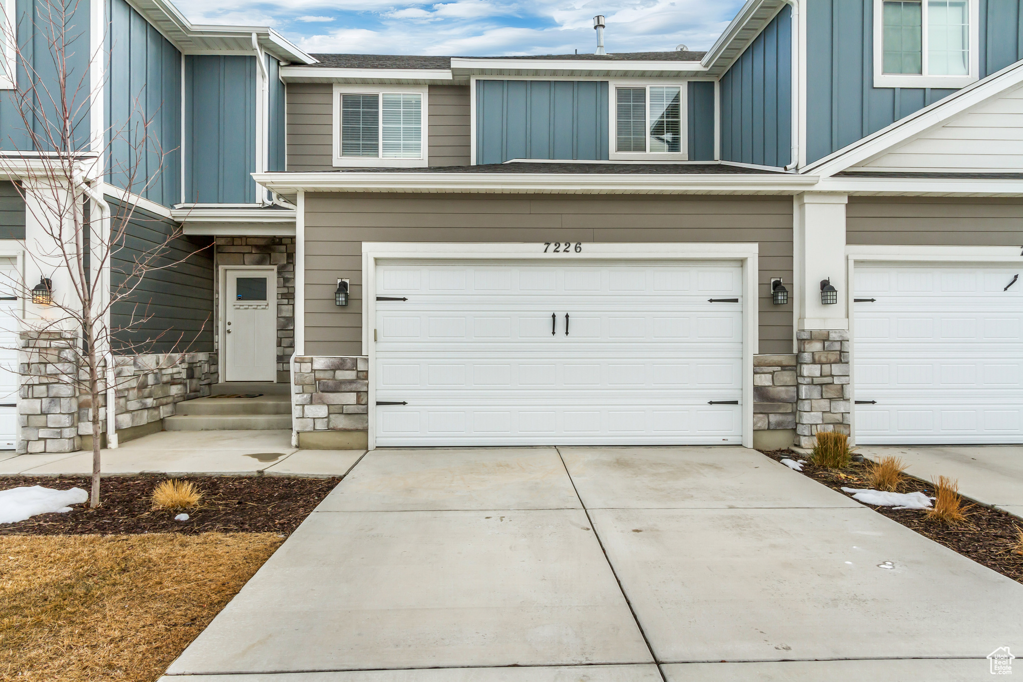 Exterior space with board and batten siding, stone siding, concrete driveway, and a garage