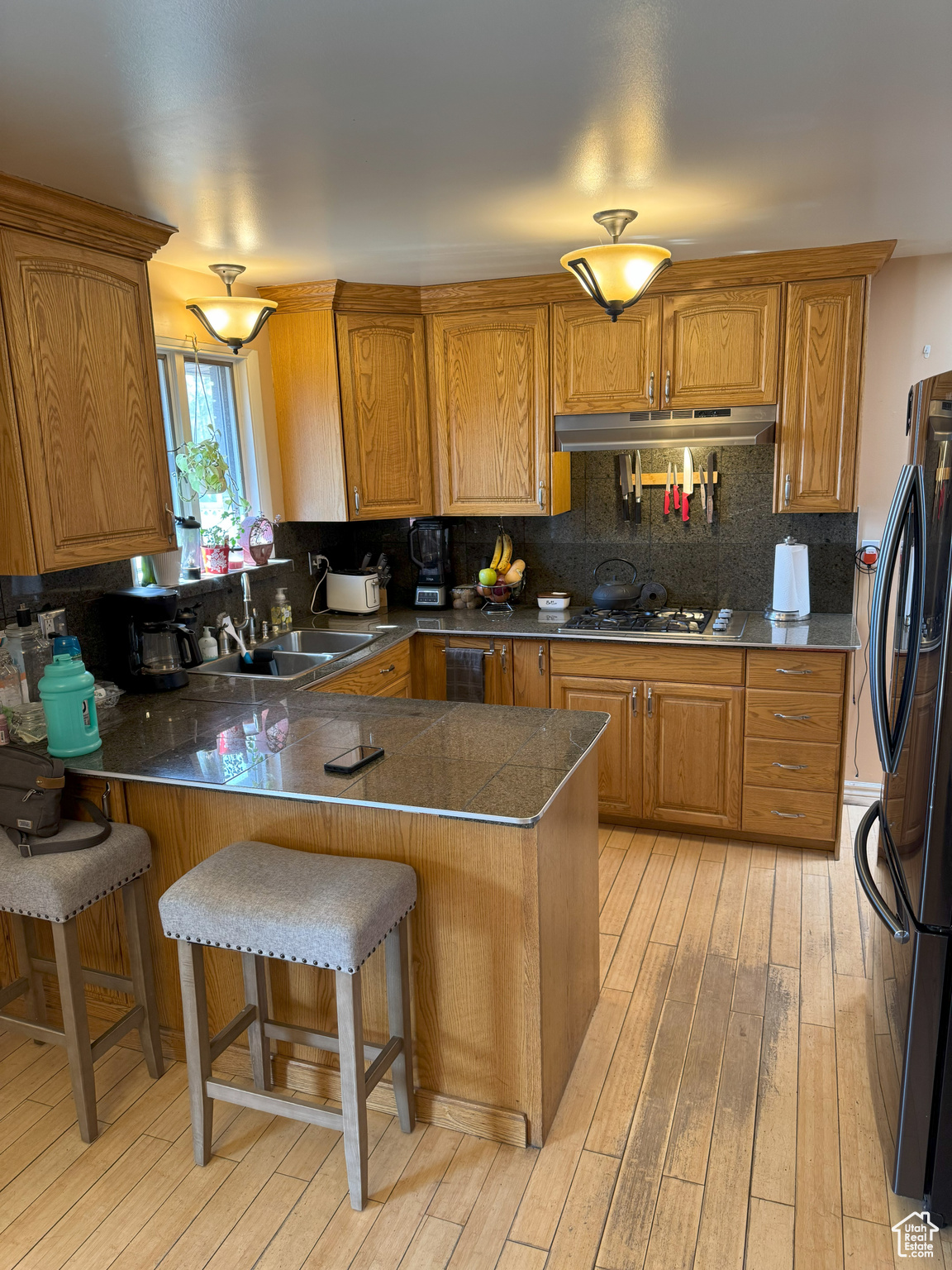 Kitchen with under cabinet range hood, a peninsula, and a breakfast bar area