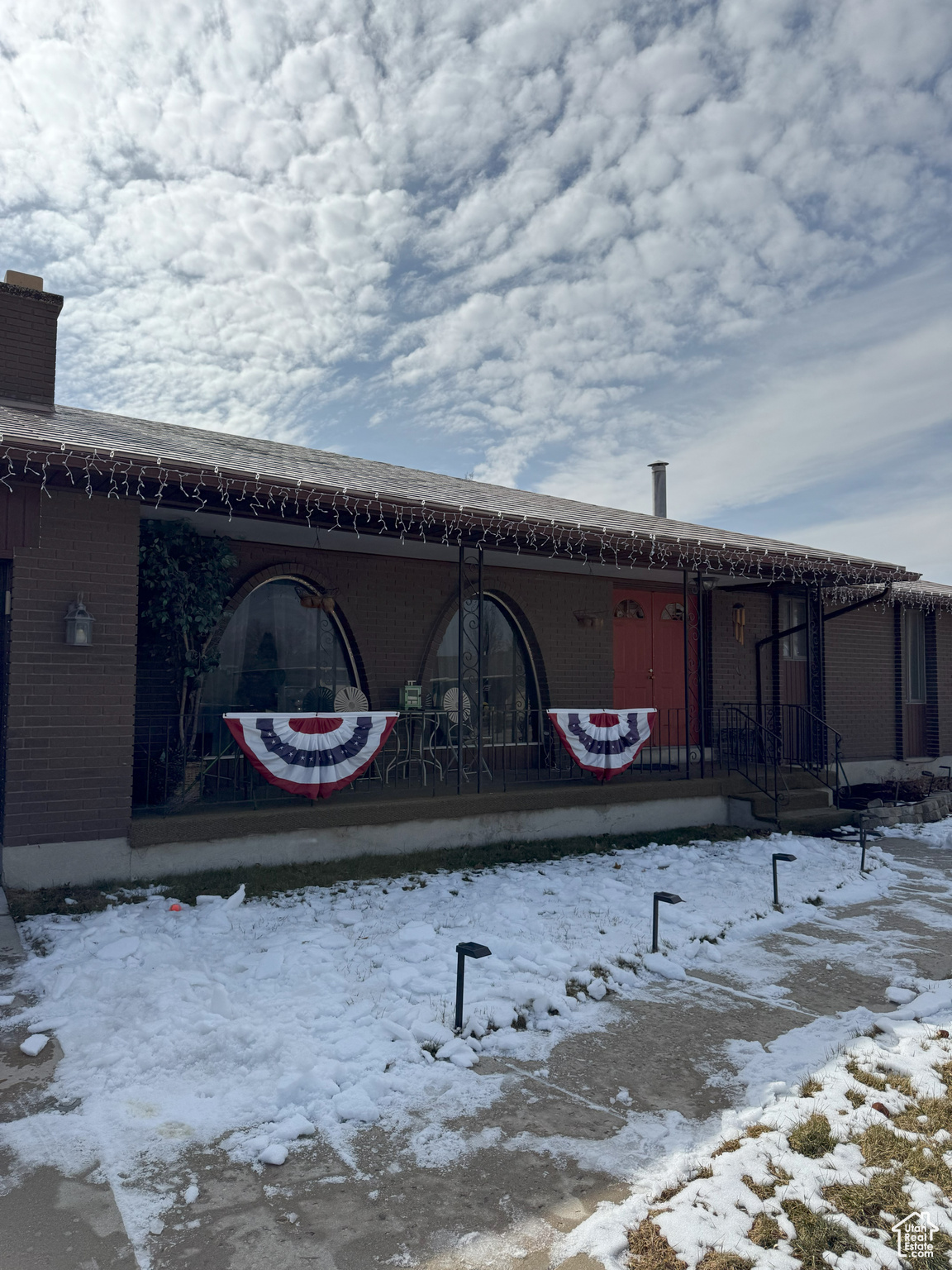 Exterior space featuring covered porch, brick siding, and a chimney