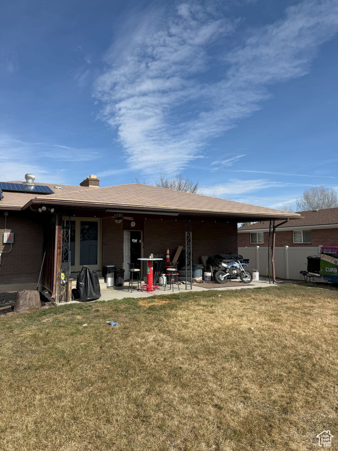 Rear view of house featuring a patio area, a yard, fence, and solar panels