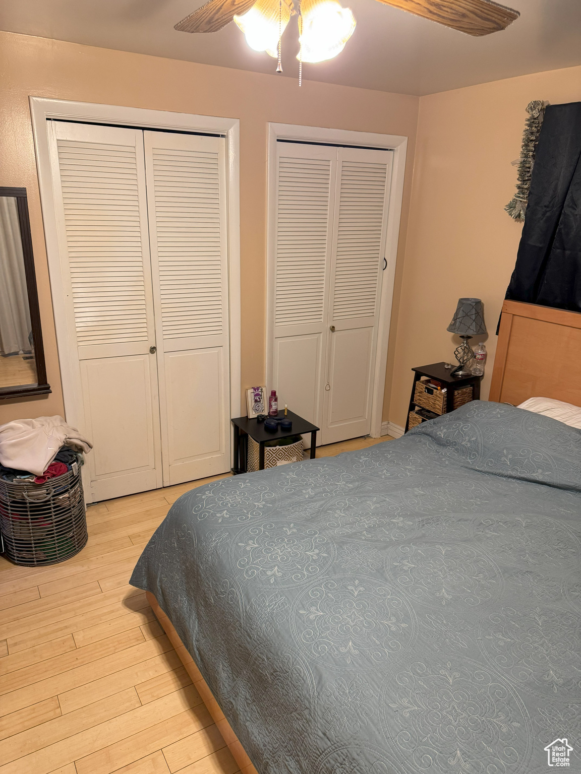 Bedroom with light wood finished floors, a ceiling fan, and multiple closets