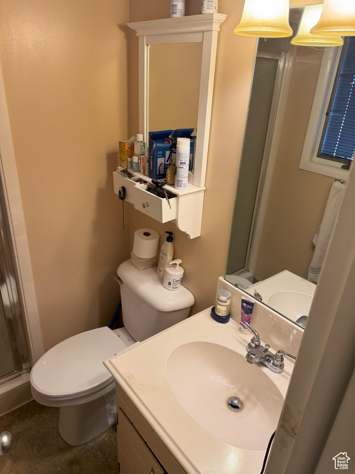 Three-quarter bathroom featuring a stall shower, vanity, toilet, and tile patterned floors