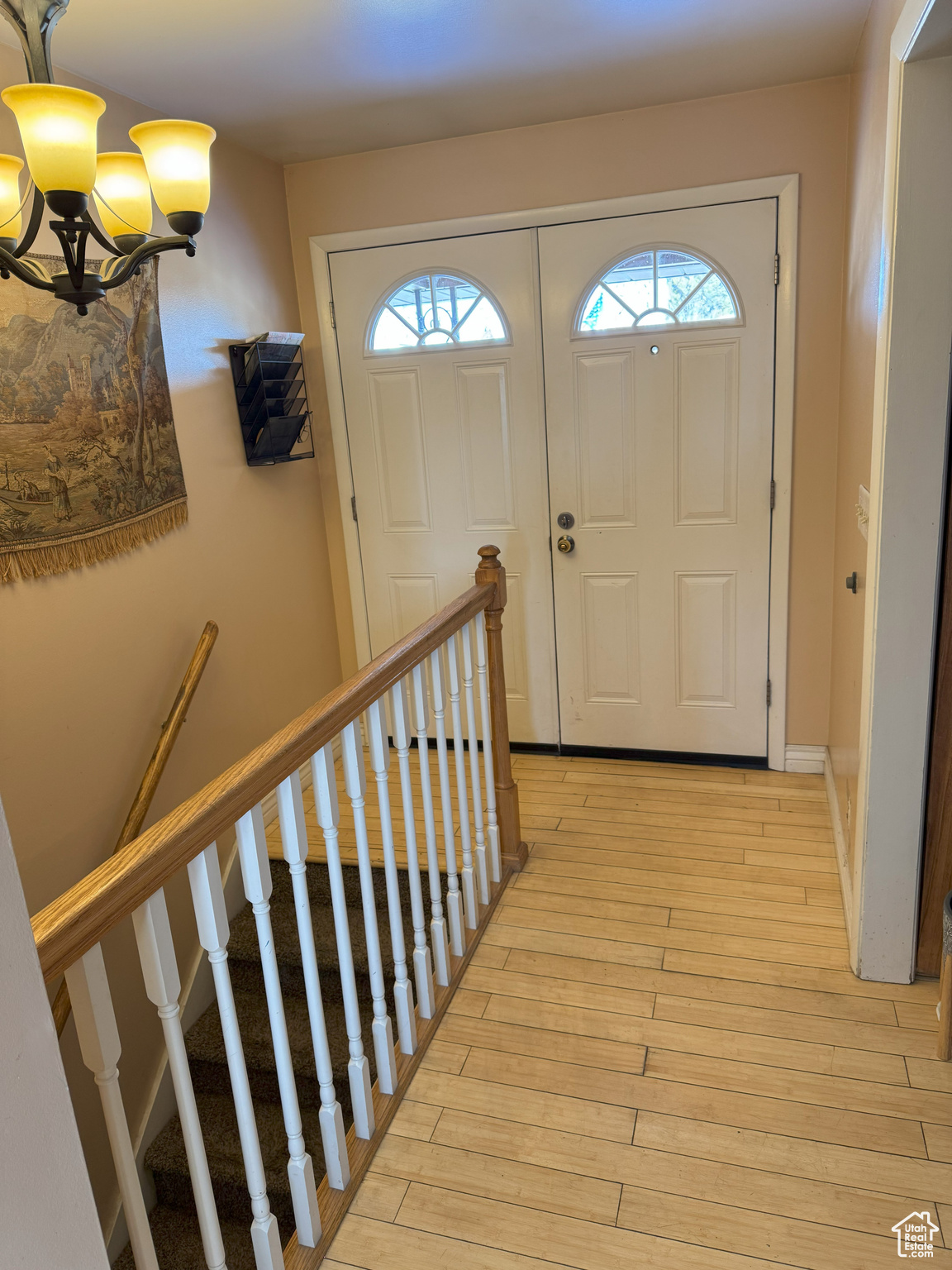 Entrance foyer featuring light wood-style flooring, baseboards, and an inviting chandelier