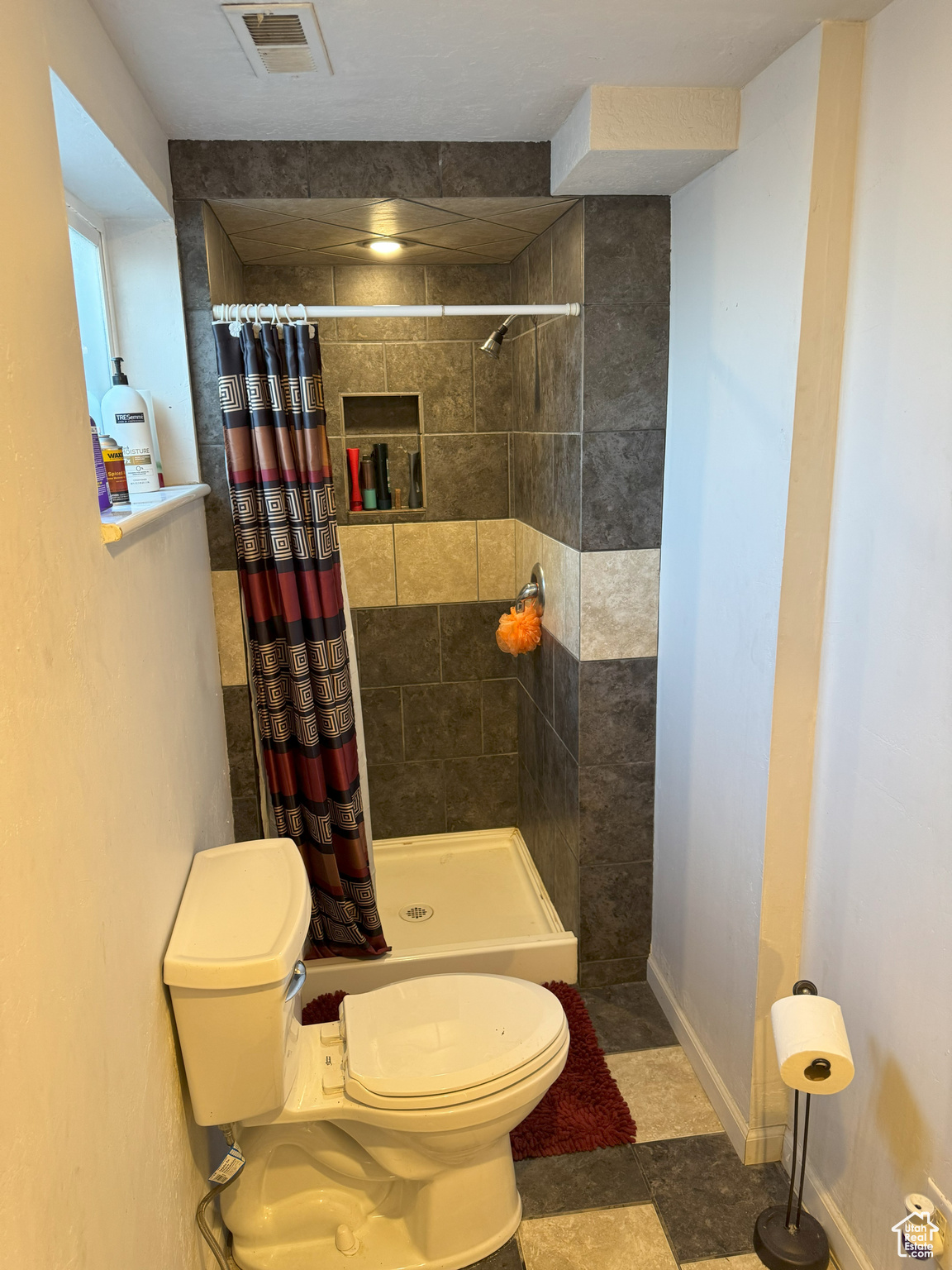 Three-quarter bathroom with baseboards, visible vents, a shower stall, and toilet