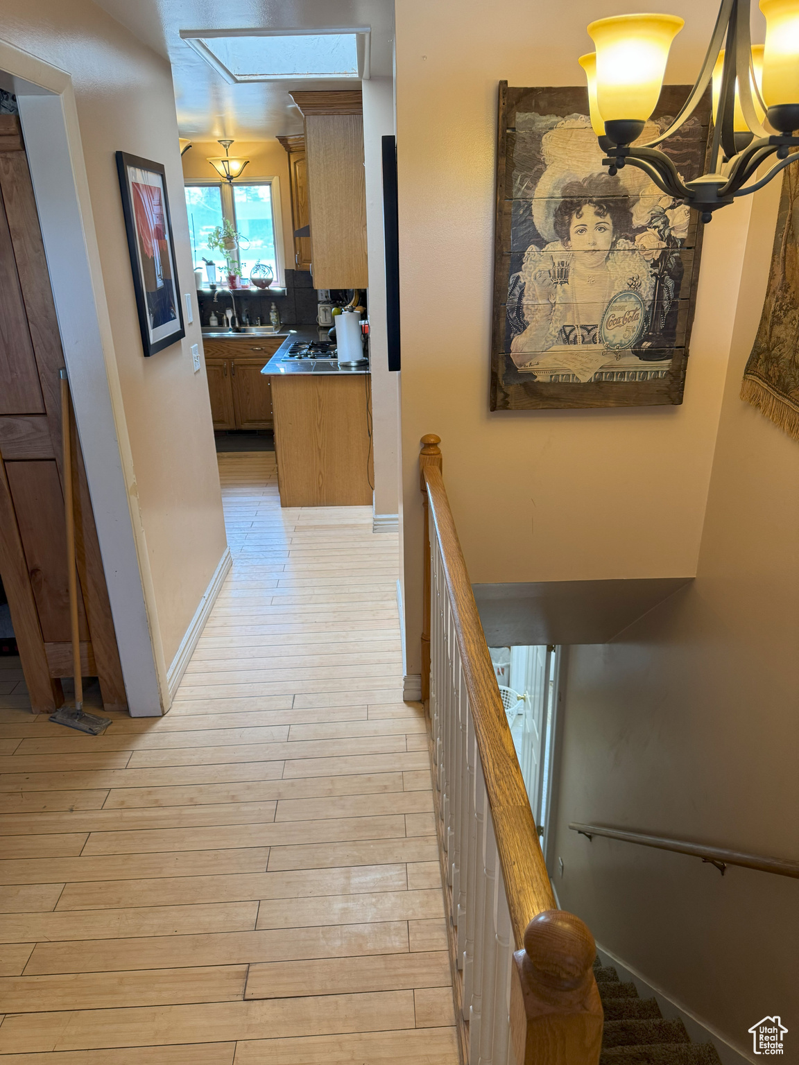 Hallway with light wood-type flooring, an upstairs landing, and baseboards