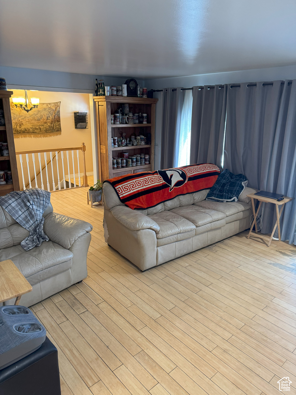 Living area with light wood-type flooring and an inviting chandelier