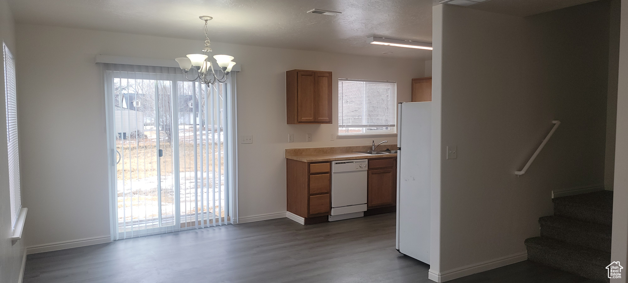 Kitchen with white appliances, visible vents, light countertops, pendant lighting, and a sink