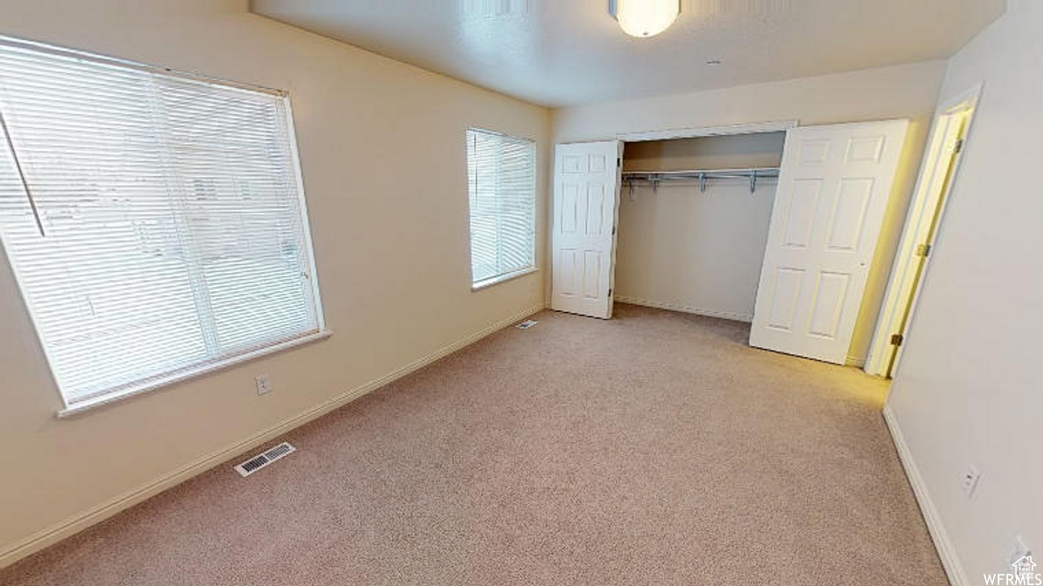 Unfurnished bedroom featuring light colored carpet, a closet, visible vents, and baseboards