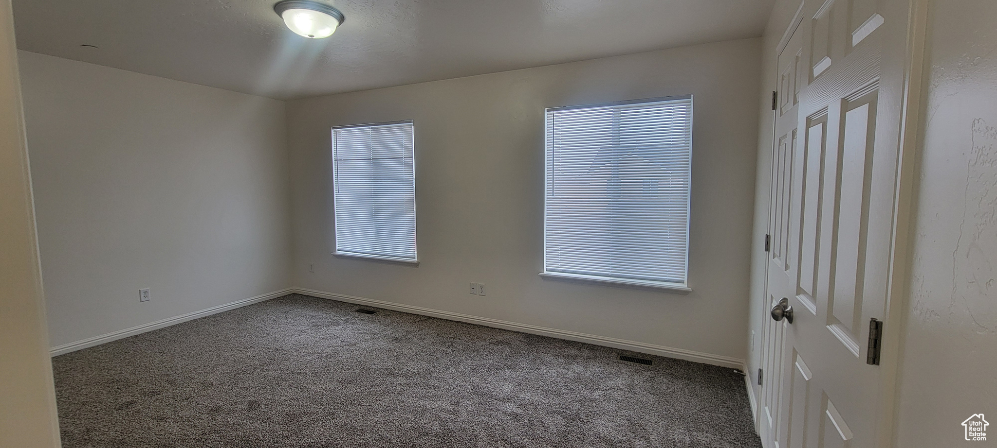 Carpeted spare room featuring a healthy amount of sunlight, visible vents, and baseboards