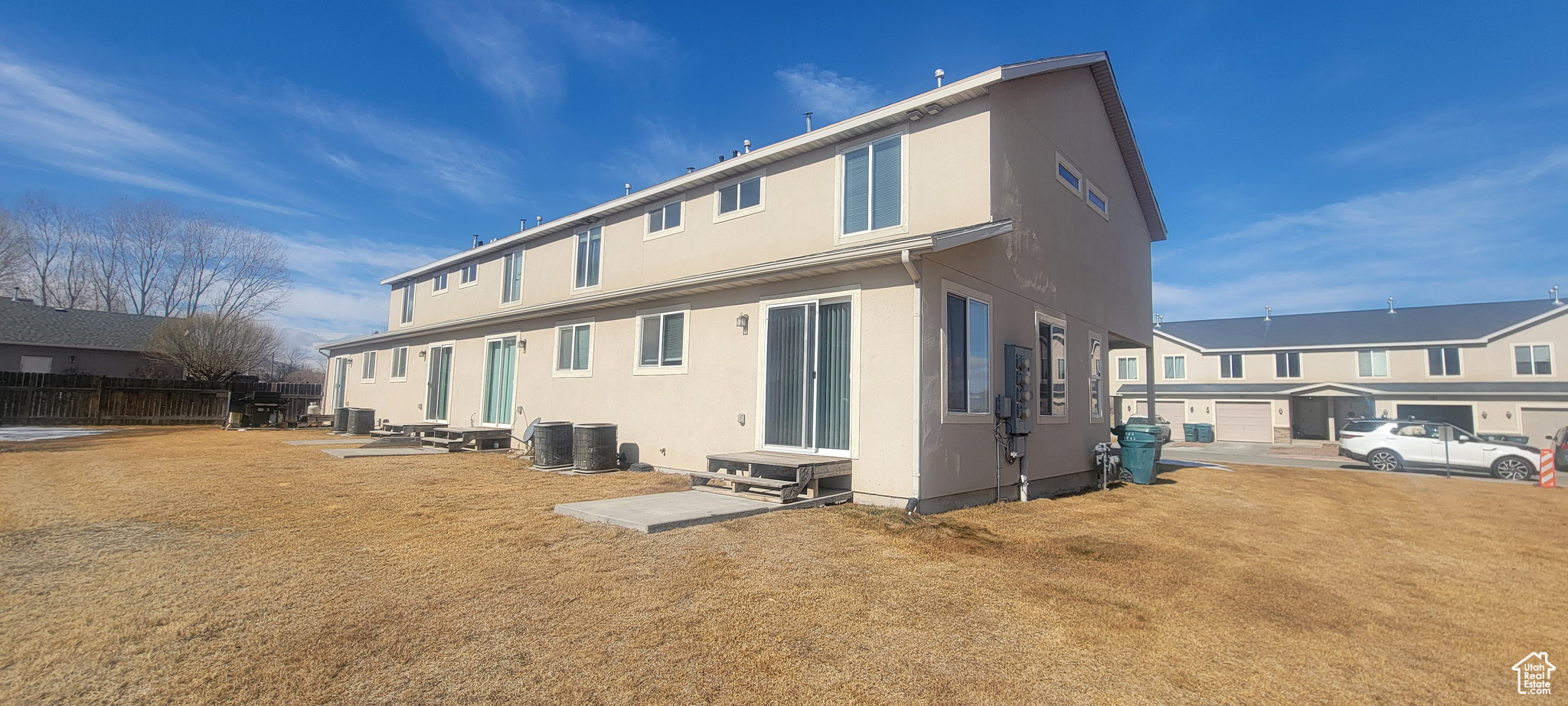 Rear view of property featuring central AC unit, a residential view, fence, and stucco siding