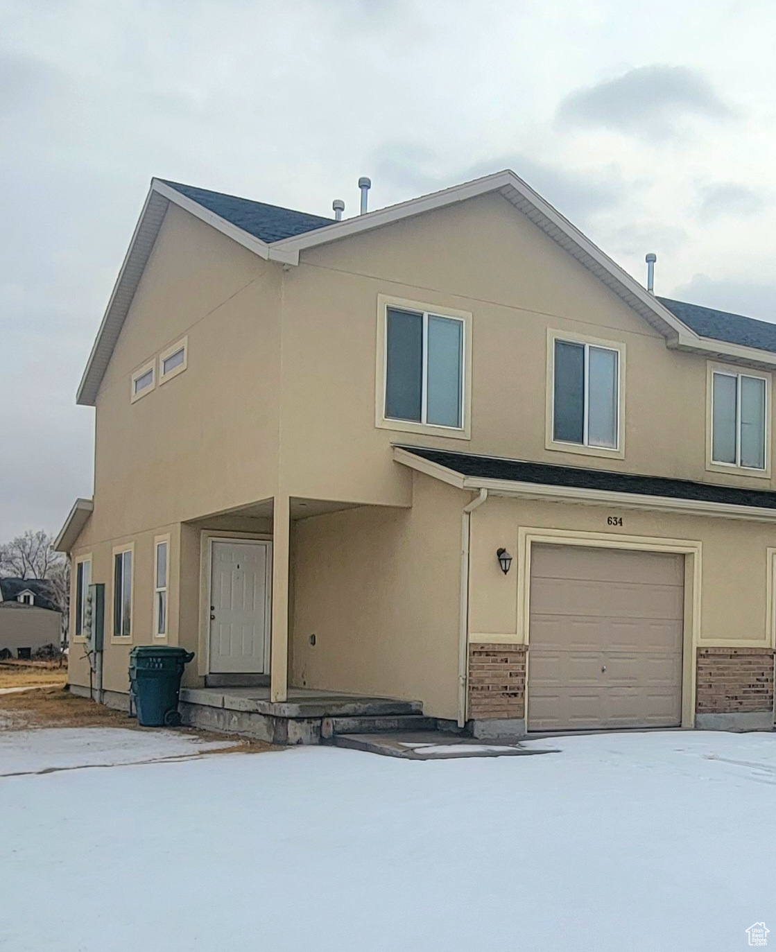 View of front of property with a garage, brick siding, and stucco siding