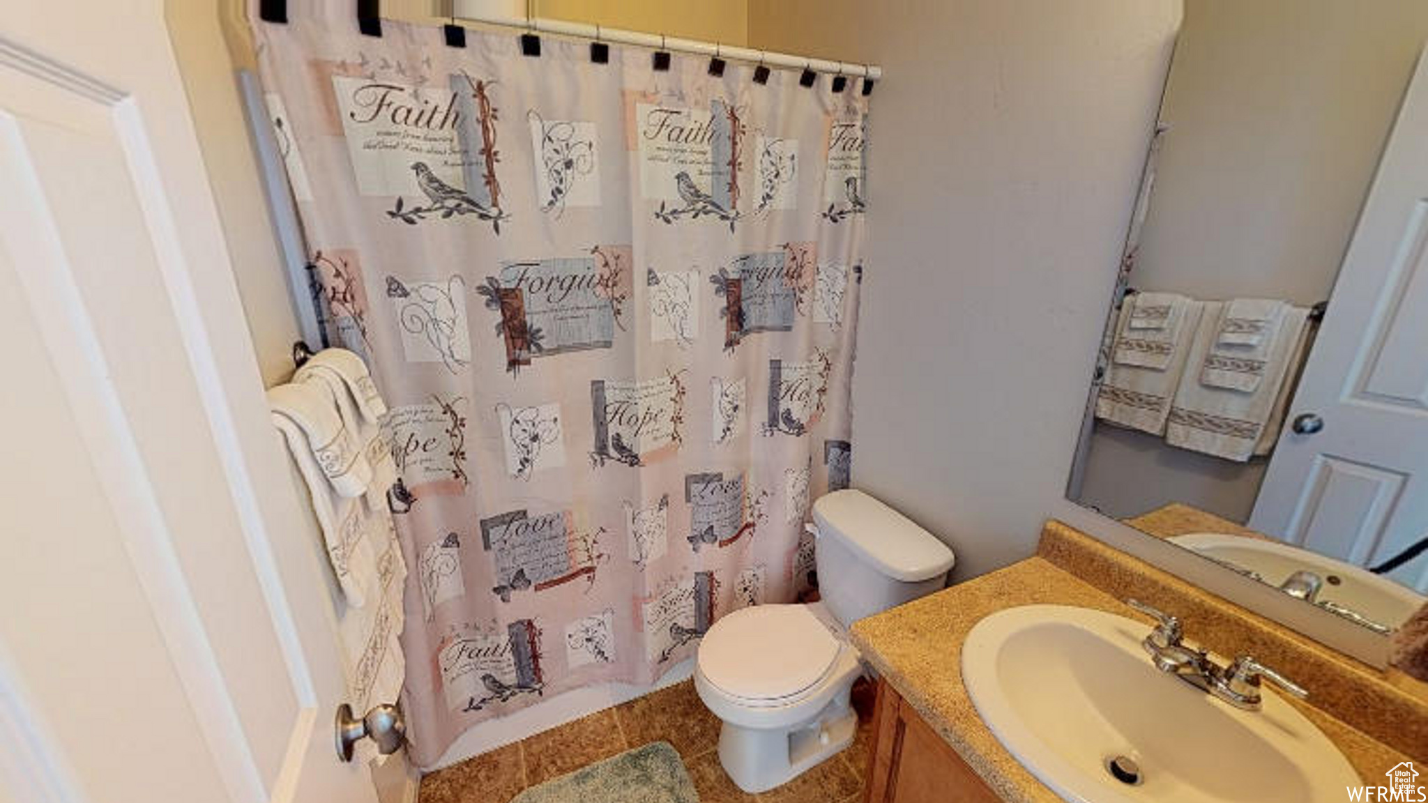 Bathroom featuring toilet, curtained shower, and vanity