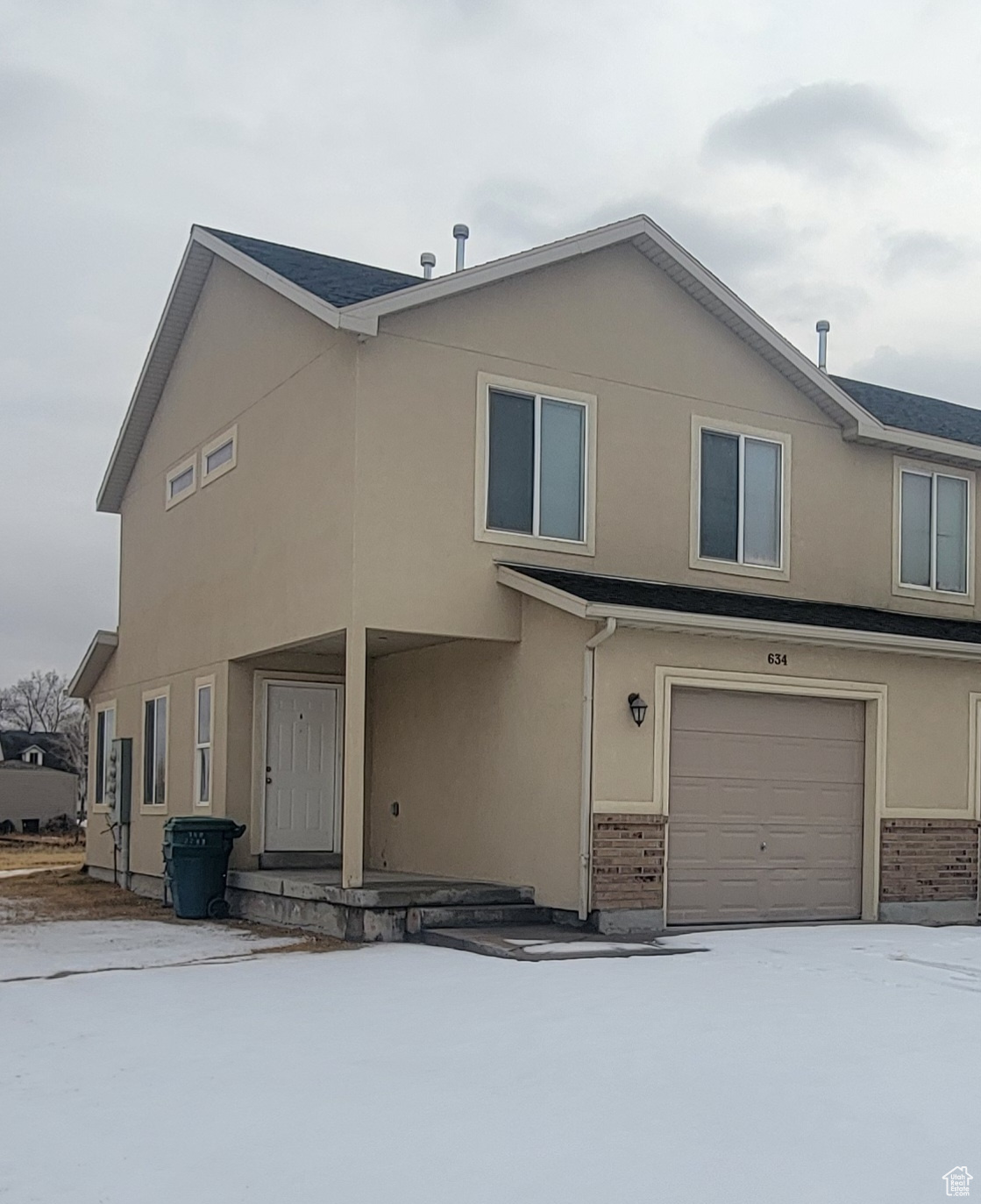 View of front of property with brick siding, an attached garage, and stucco siding