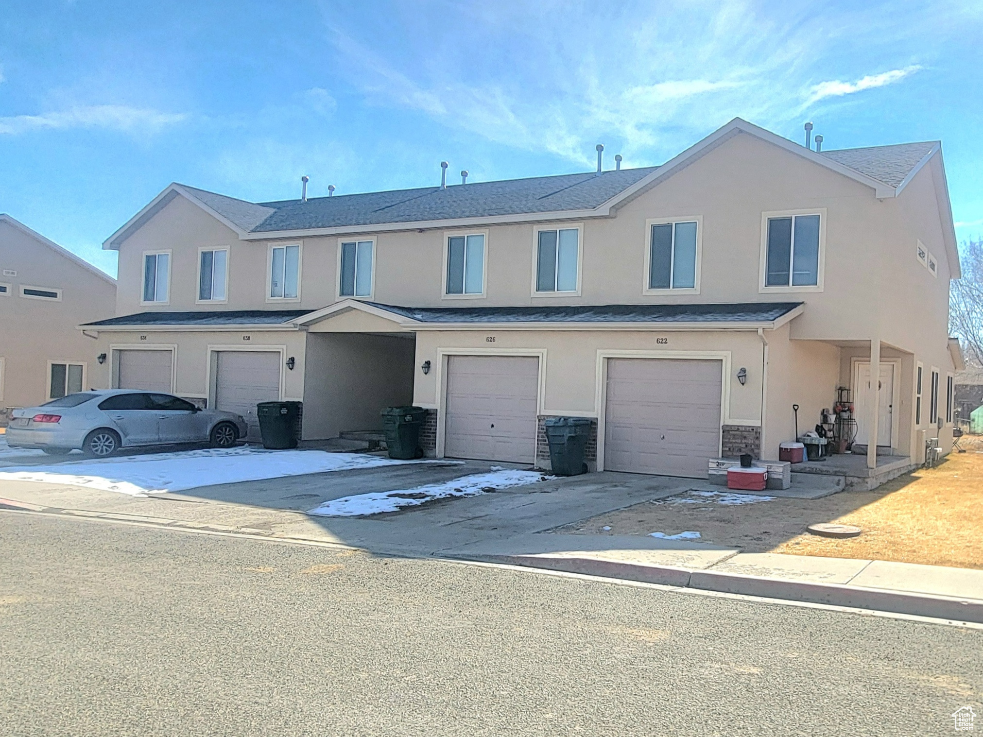 Multi unit property featuring driveway, a garage, and stucco siding