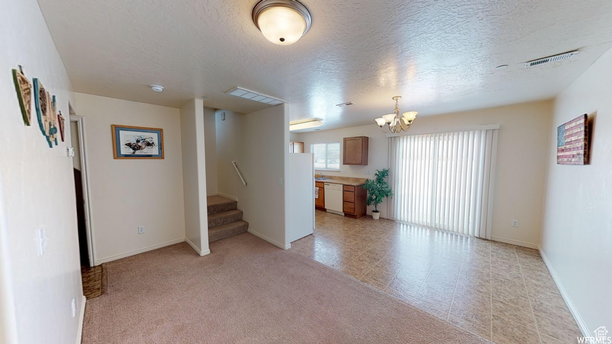 Unfurnished living room with stairs, visible vents, a chandelier, and a textured ceiling