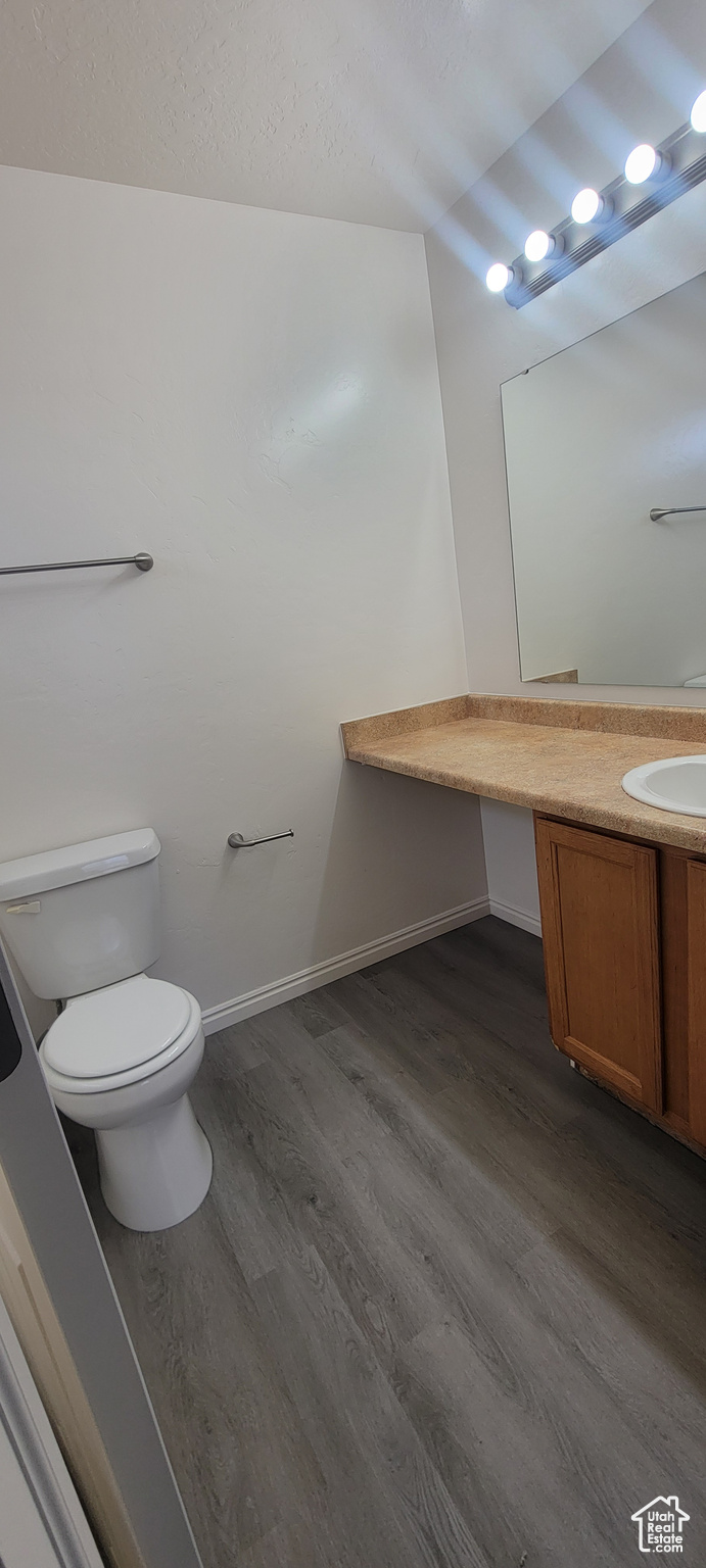 Bathroom featuring baseboards, vanity, toilet, and wood finished floors