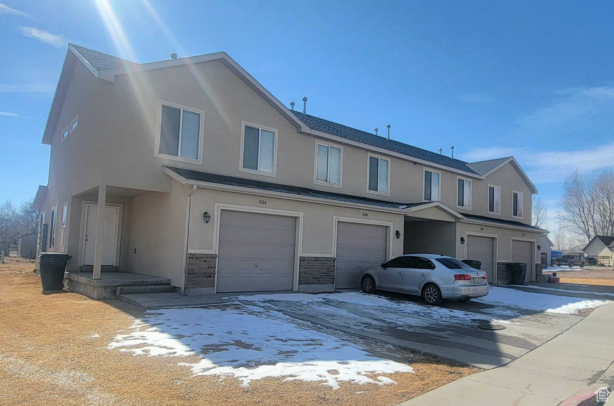 Townhome / multi-family property featuring stone siding, an attached garage, and stucco siding