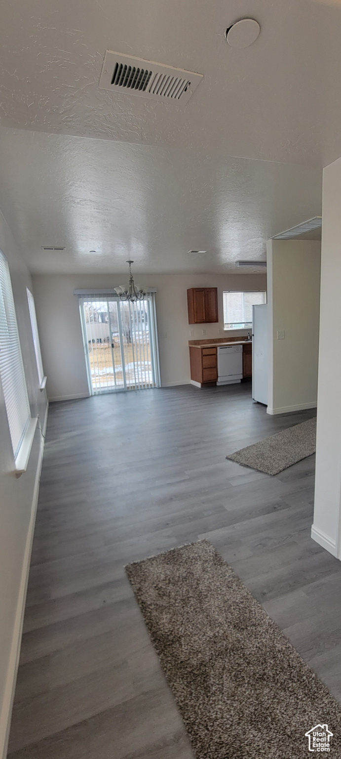 Unfurnished living room with a healthy amount of sunlight, visible vents, baseboards, and dark wood-style flooring