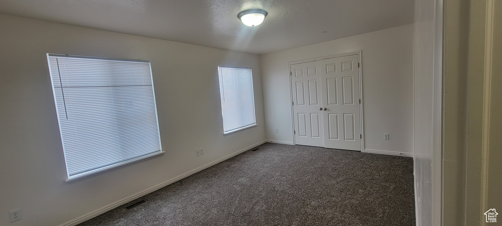 Unfurnished bedroom with a closet, dark carpet, and baseboards