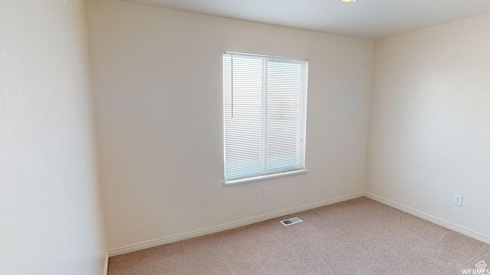 Spare room featuring baseboards, visible vents, and light colored carpet