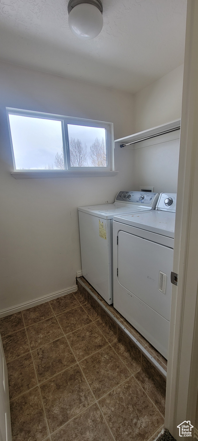 Laundry area with laundry area, dark tile patterned flooring, washer and clothes dryer, and baseboards